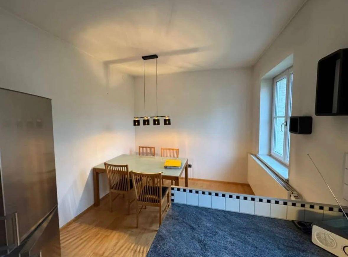 Essbereich in der Küche mit Esstisch und Stühlen, beleuchtet durch eine moderne Hängelampe.