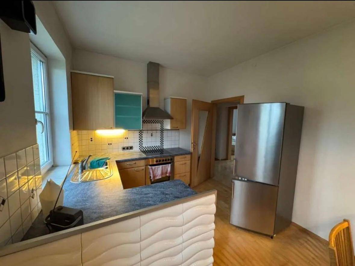 Funktionale Küche mit Arbeitsplatte, Spüle, Herd und Kühlschrank, bietet ausreichend Platz.