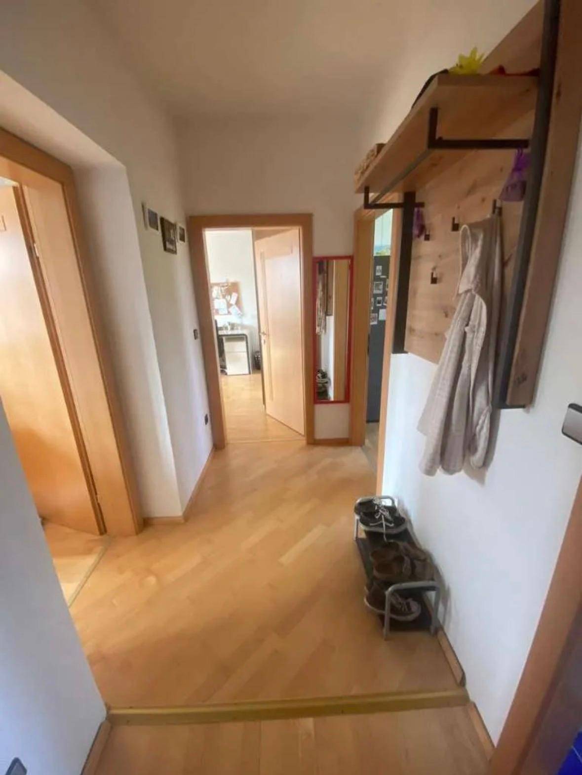 Heller Flur mit Holzfußboden, Garderobe und Schuhregal, führt zu weiteren Räumen.