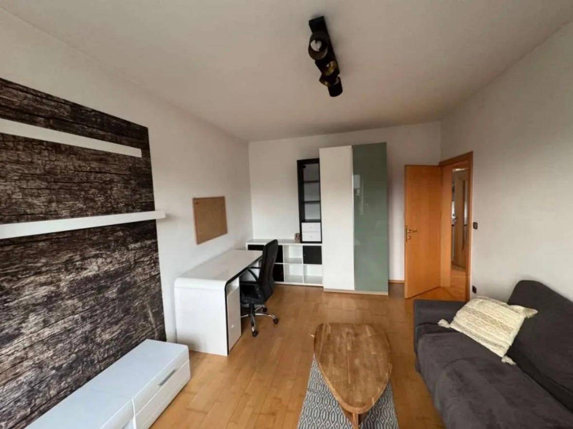 Wohnzimmer mit Schreibtisch, Sofa und Medieneinheit, bietet eine funktionale und gemütliche Einrichtung.