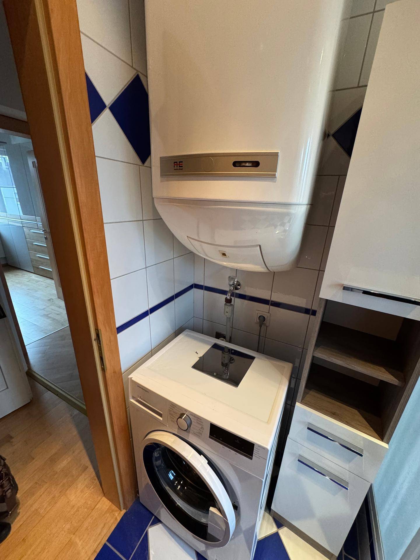 Kleiner Raum mit Waschmaschine und Warmwasserboiler, ideal für Haushaltsgeräte.