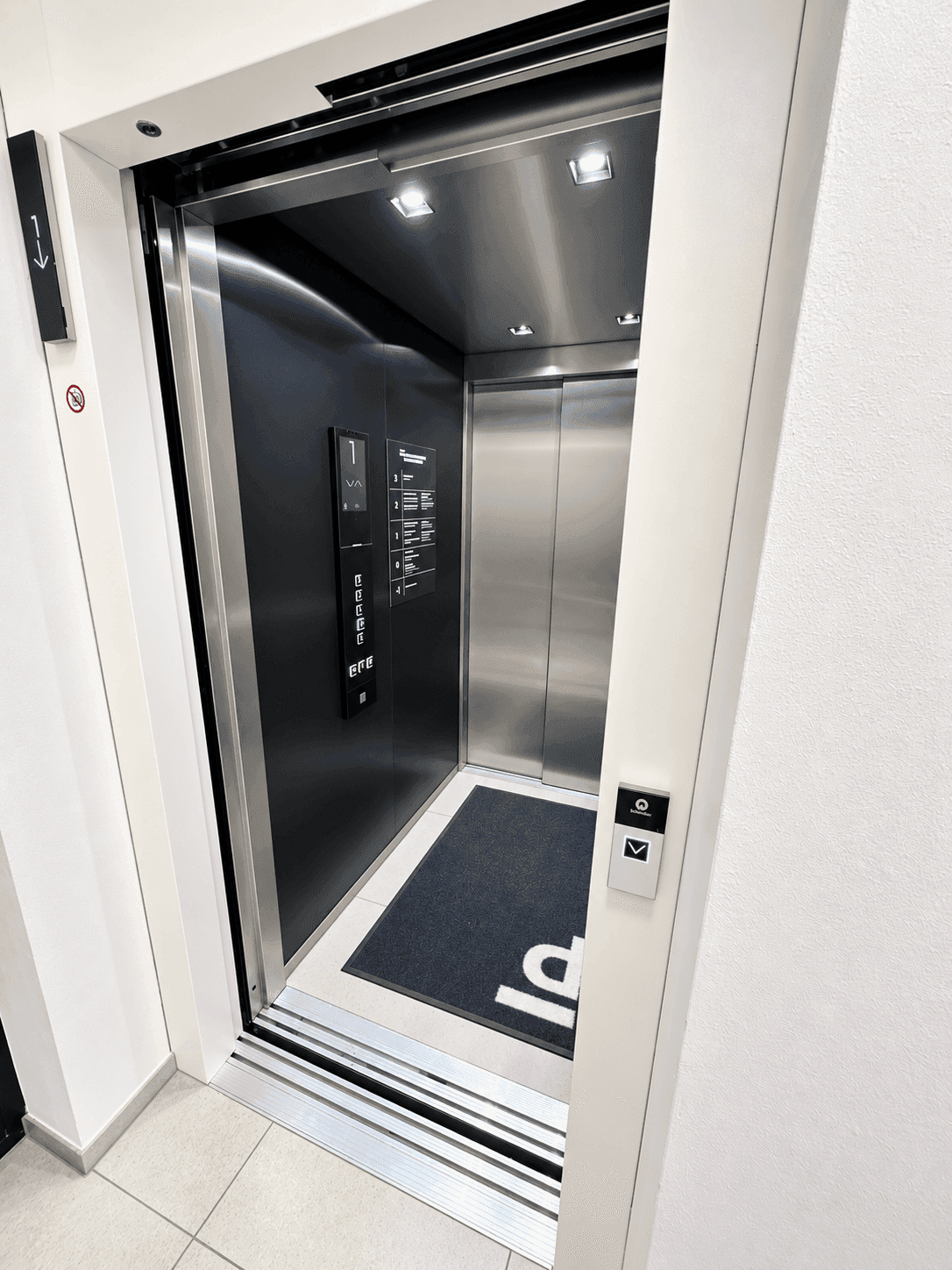 Moderner Aufzug mit Edelstahloberflächen und digitaler Anzeige in einem gepflegten Gebäude.