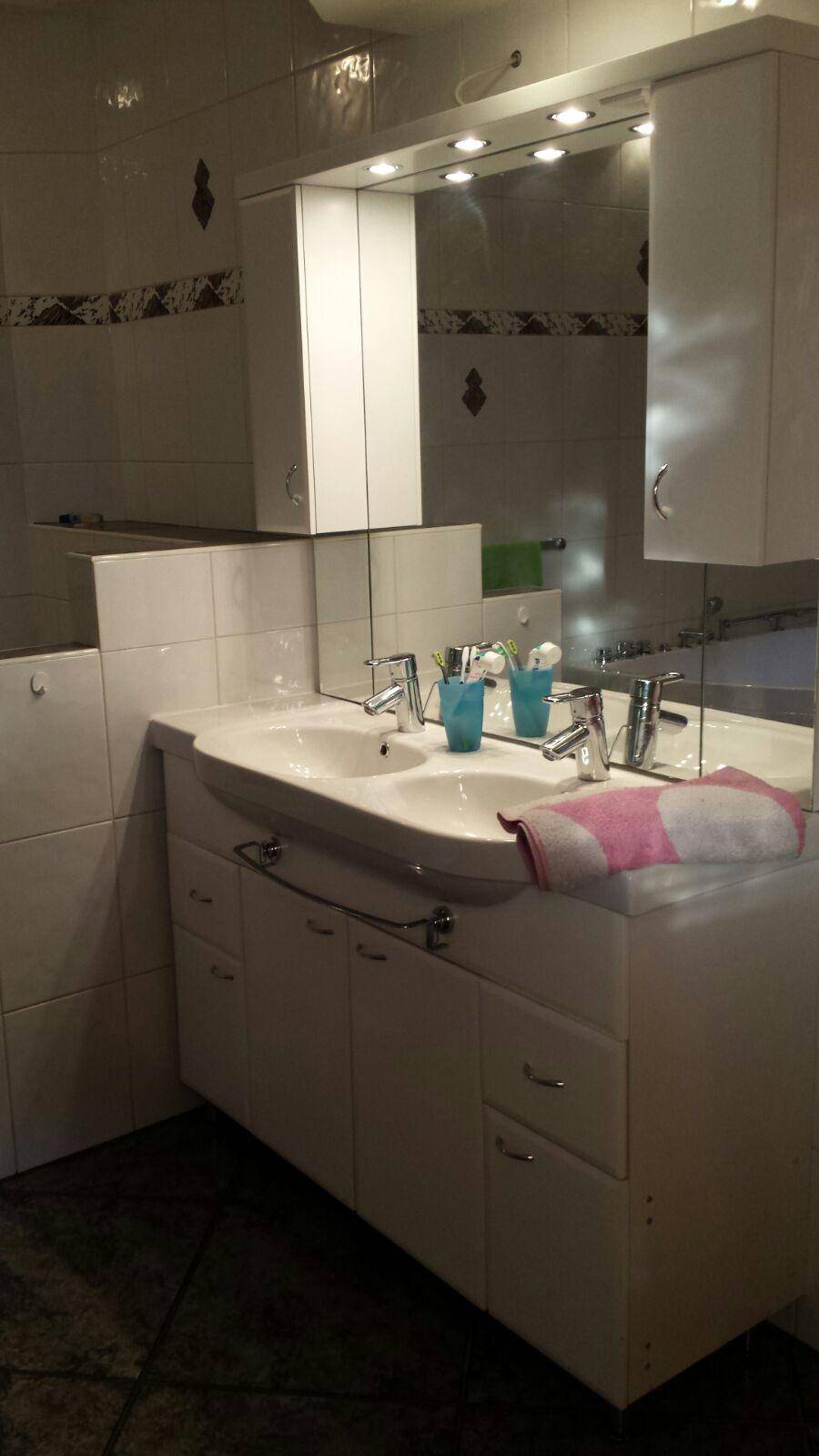Badezimmer mit Doppelwaschbecken, Spiegelschrank und Fliesen.