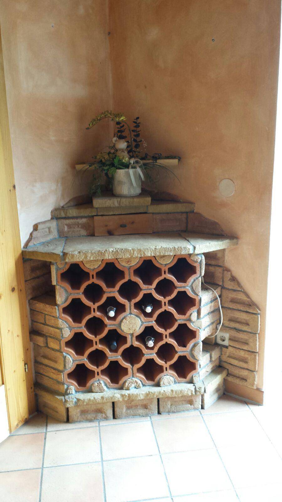 Rustikales Weinregal aus Ziegeln und Terrakotta in einer Ecke des Raumes.