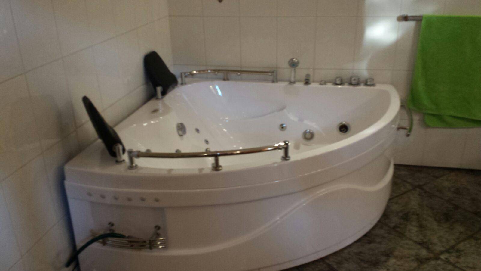 Badezimmer mit großer Eckbadewanne und Fliesen an den Wänden.