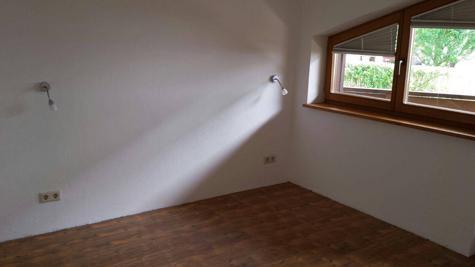 Helles Schlafzimmer mit Holzboden und schrägen Fenstern unter dem Dach.