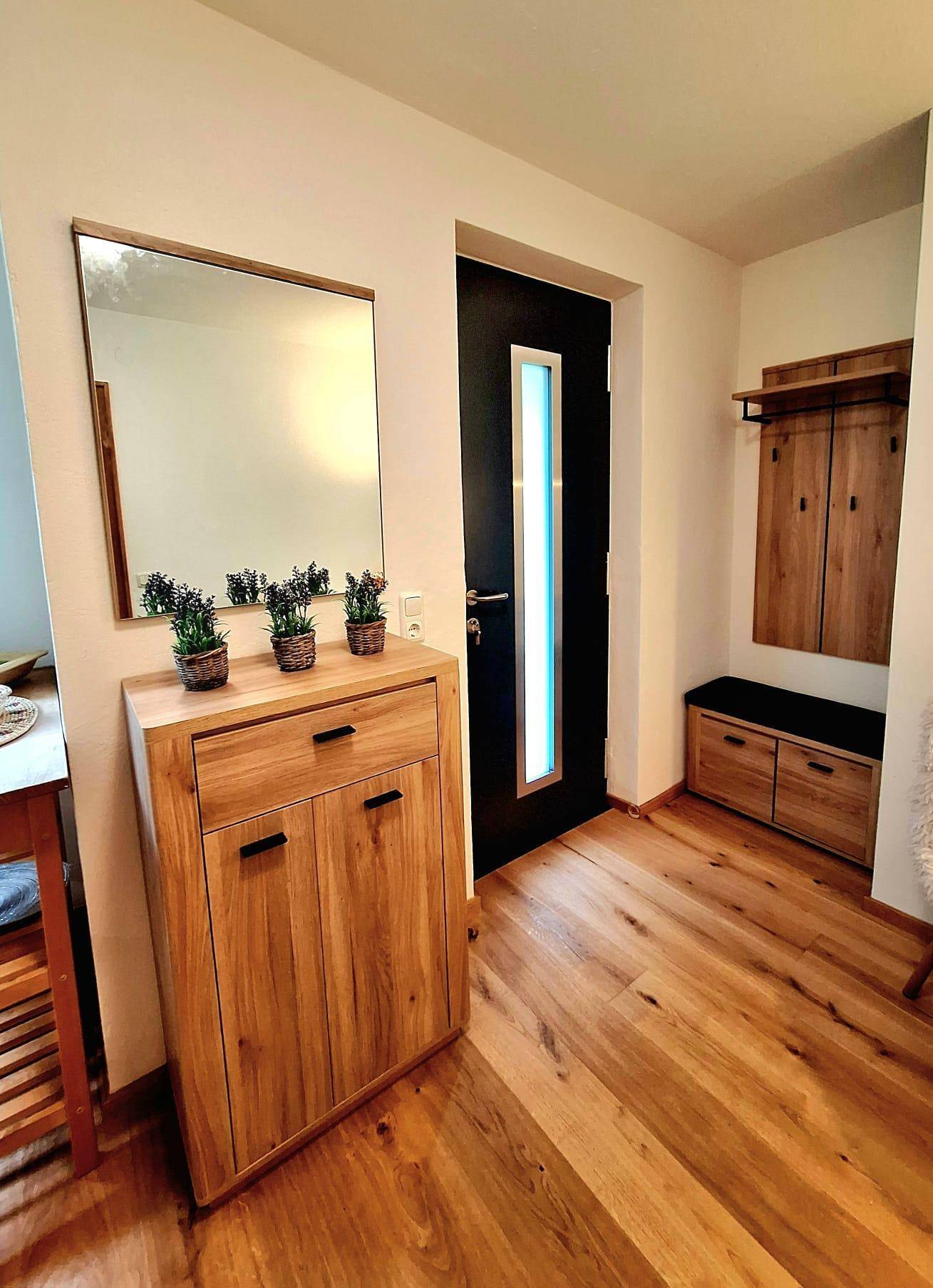 Heller Eingangsbereich mit Holzboden, Schuhschrank und Garderobe.