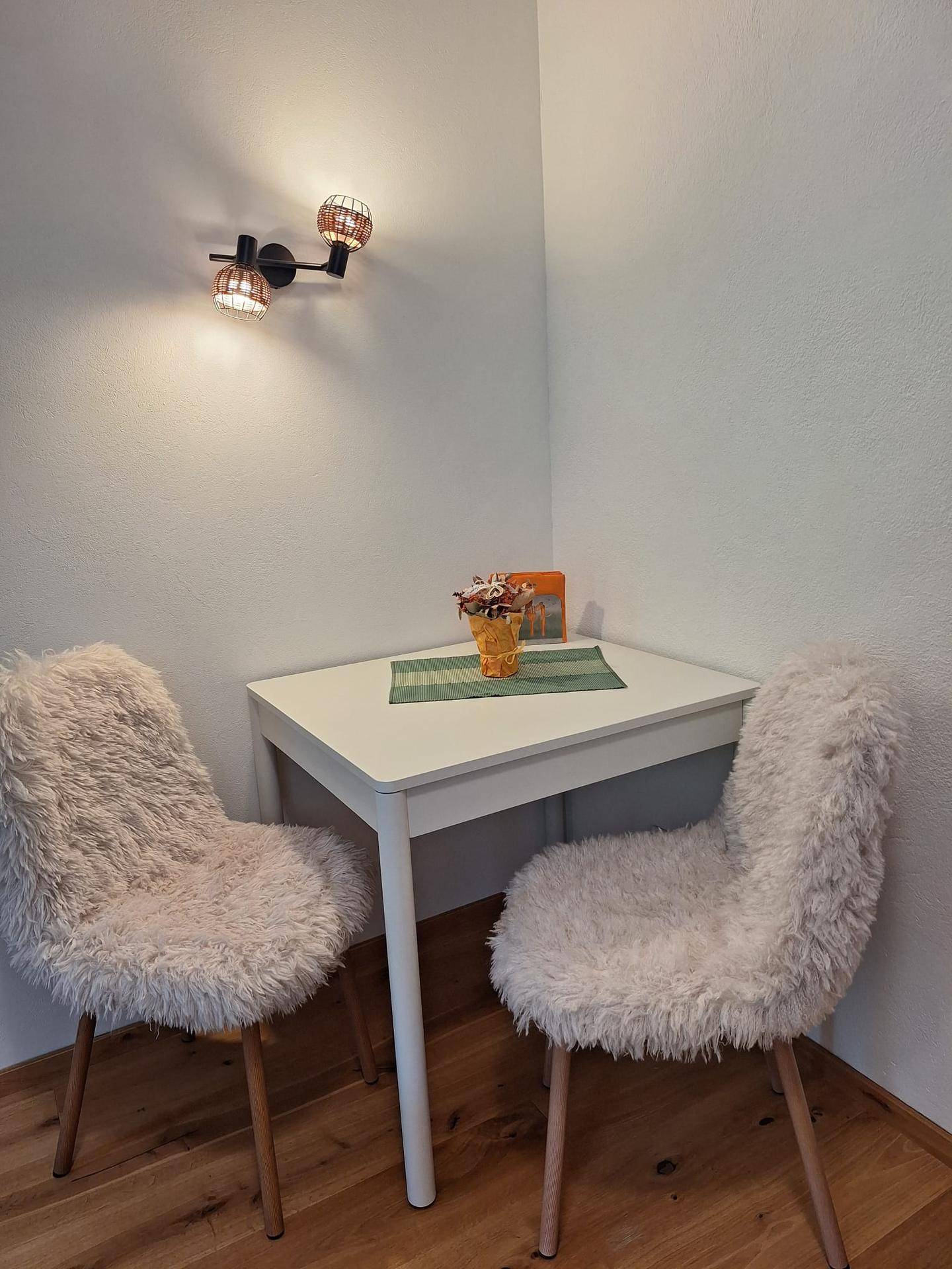 Gemütlicher Essbereich mit kleinem Tisch und zwei flauschigen Stühlen in einer Ecke.