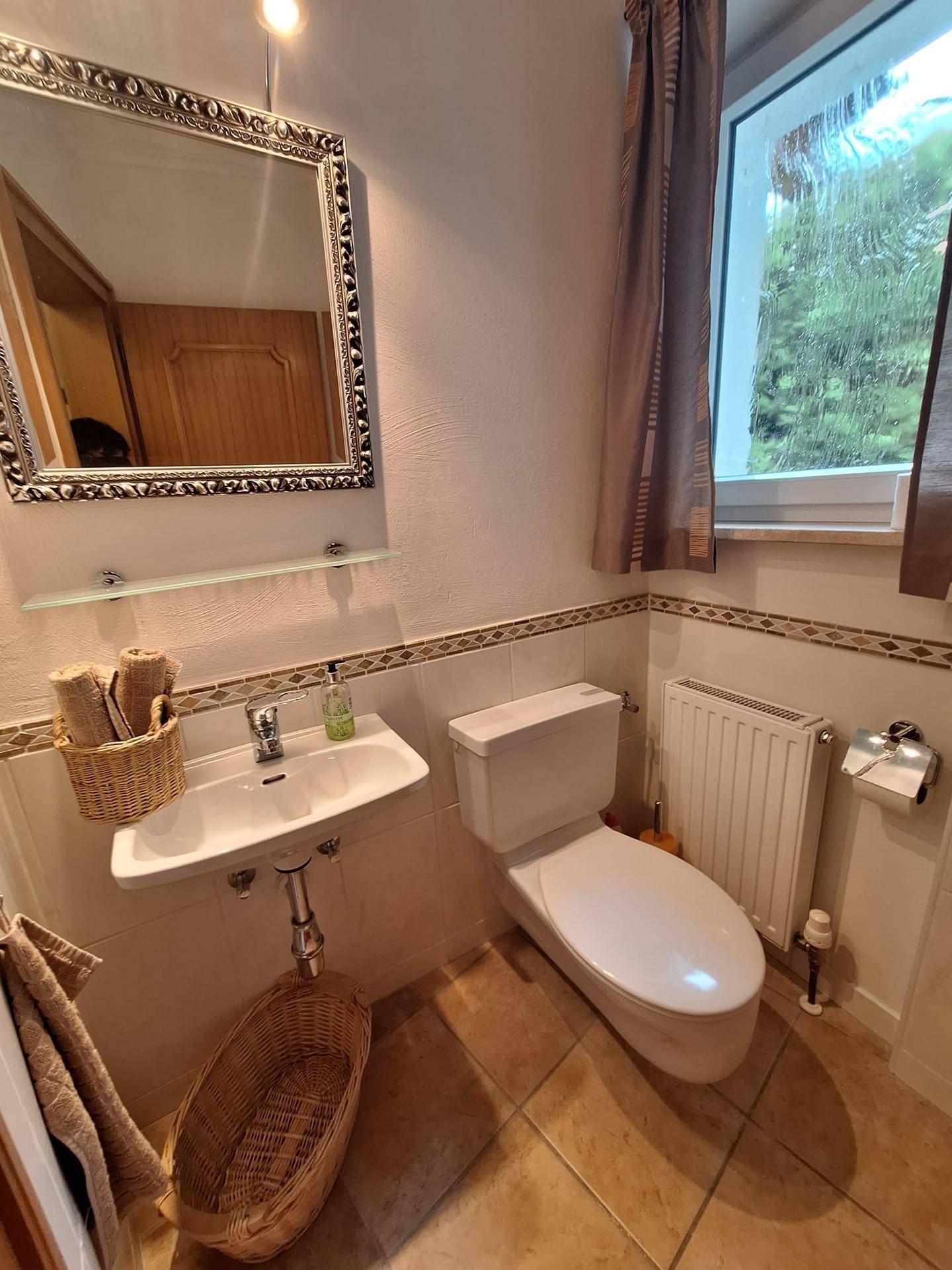 Helles Gäste-WC mit Waschbecken, Toilette und Spiegel.