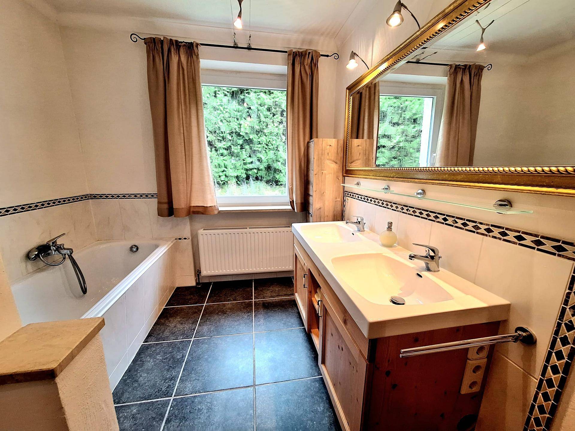 Geräumiges Badezimmer mit Doppelwaschbecken, Badewanne und Fenster.