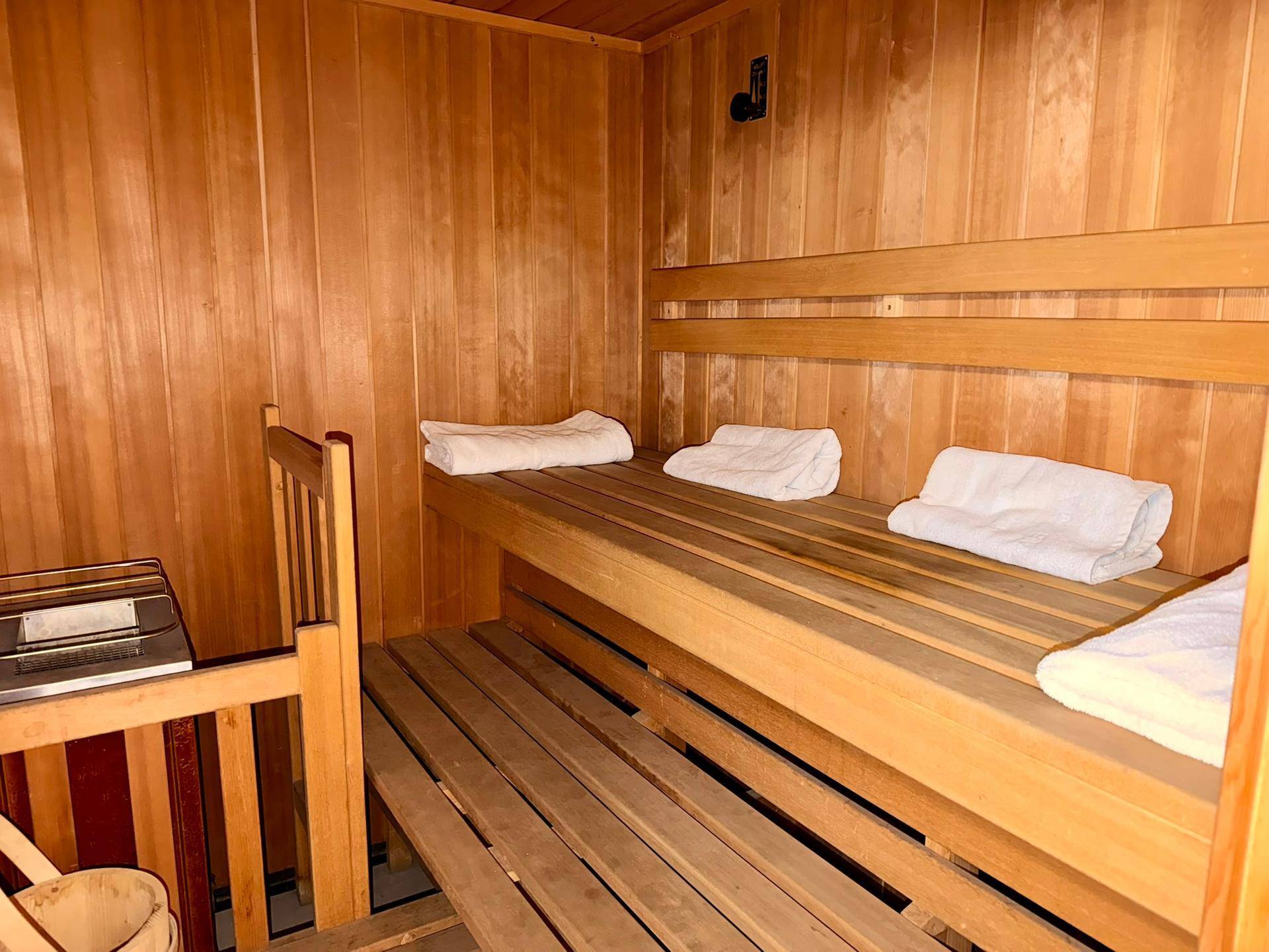 Traditionelle Holzsauna mit Bänken und Heizofen für entspannende Momente.