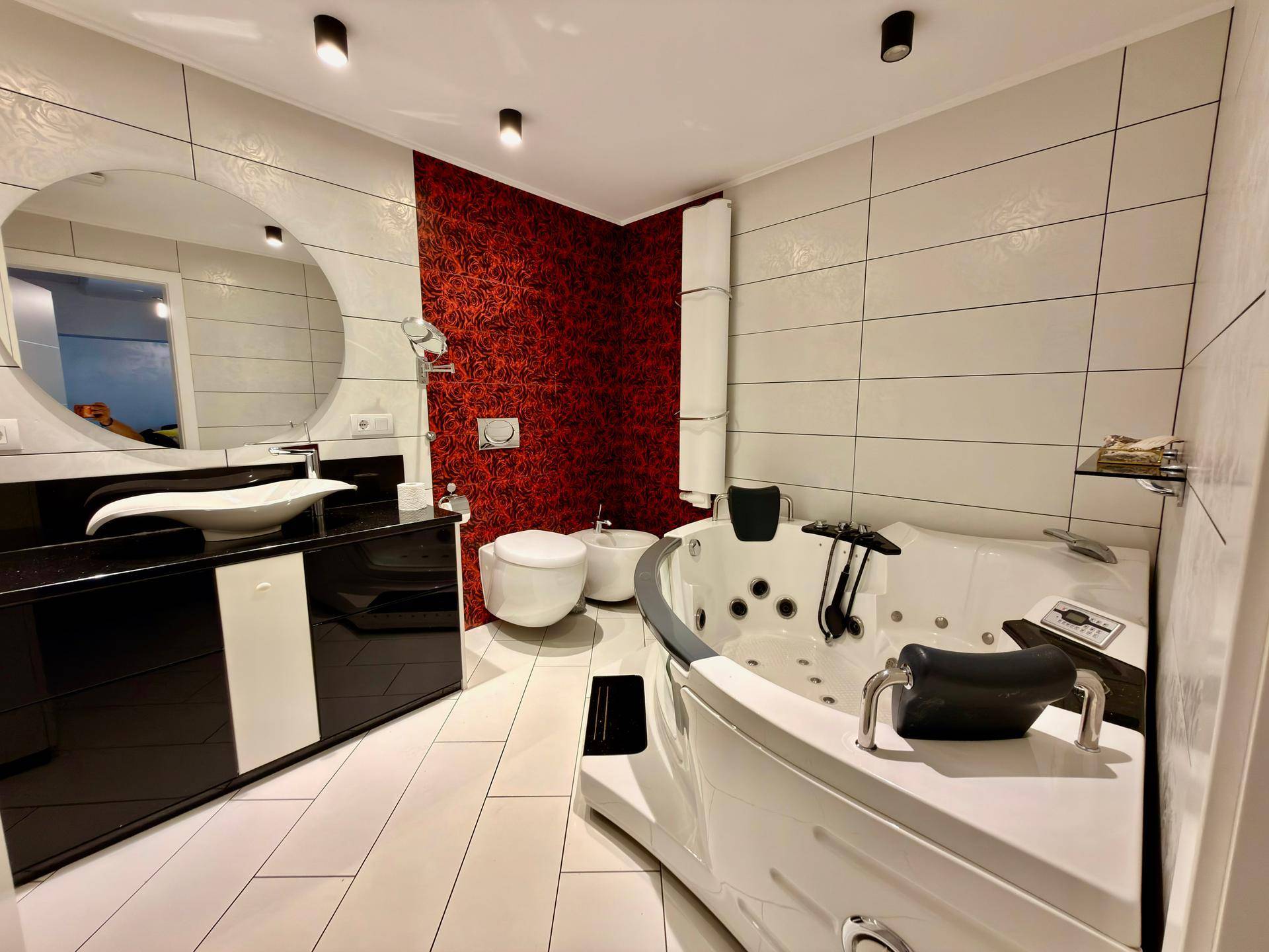 Luxuriöses Badezimmer mit großer Eck-Whirlpool-Badewanne, Bidet und modernem Waschtisch.
