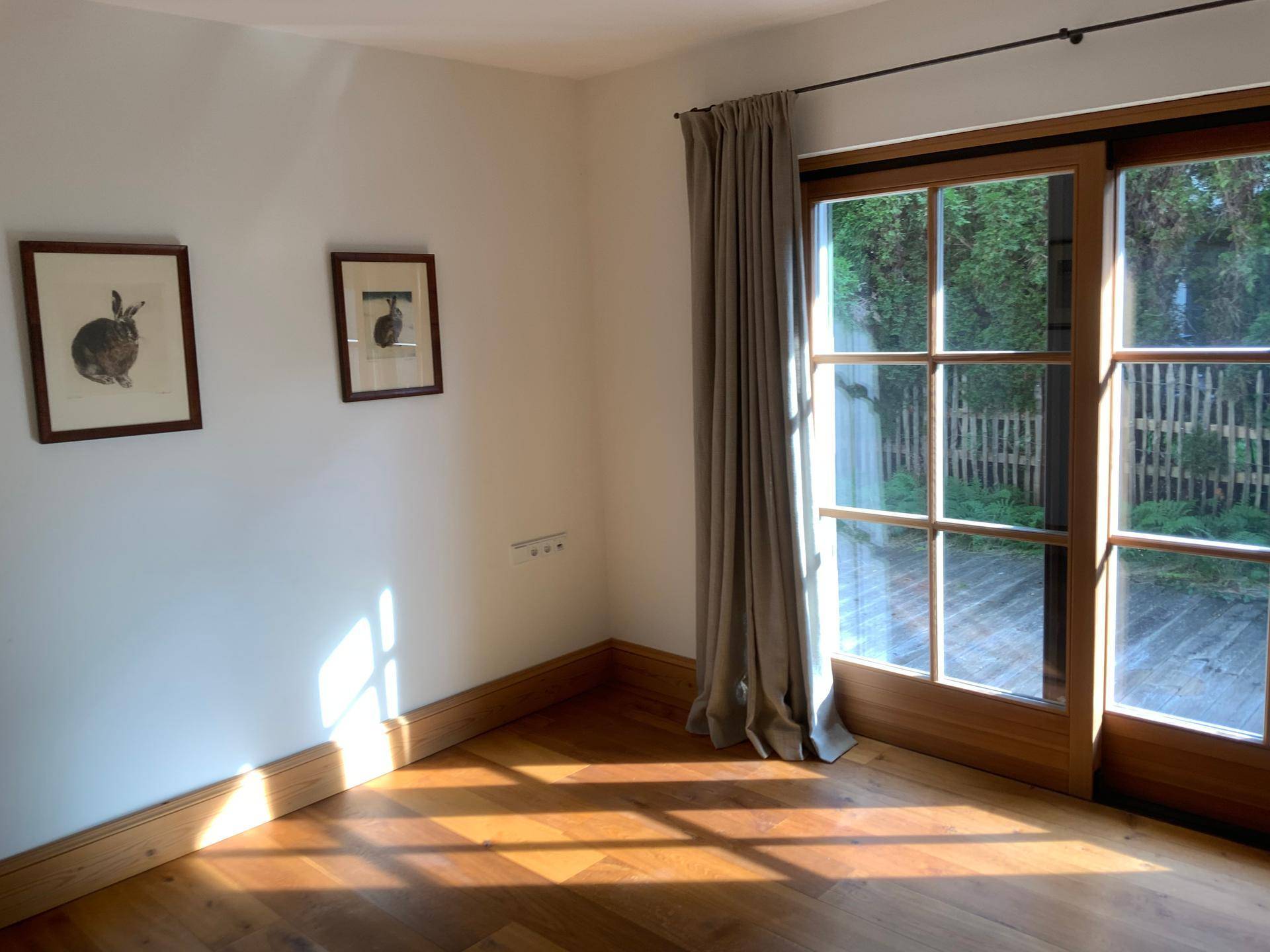 Heller Raum mit Holzboden und großen Glasschiebetüren zum Außenbereich.