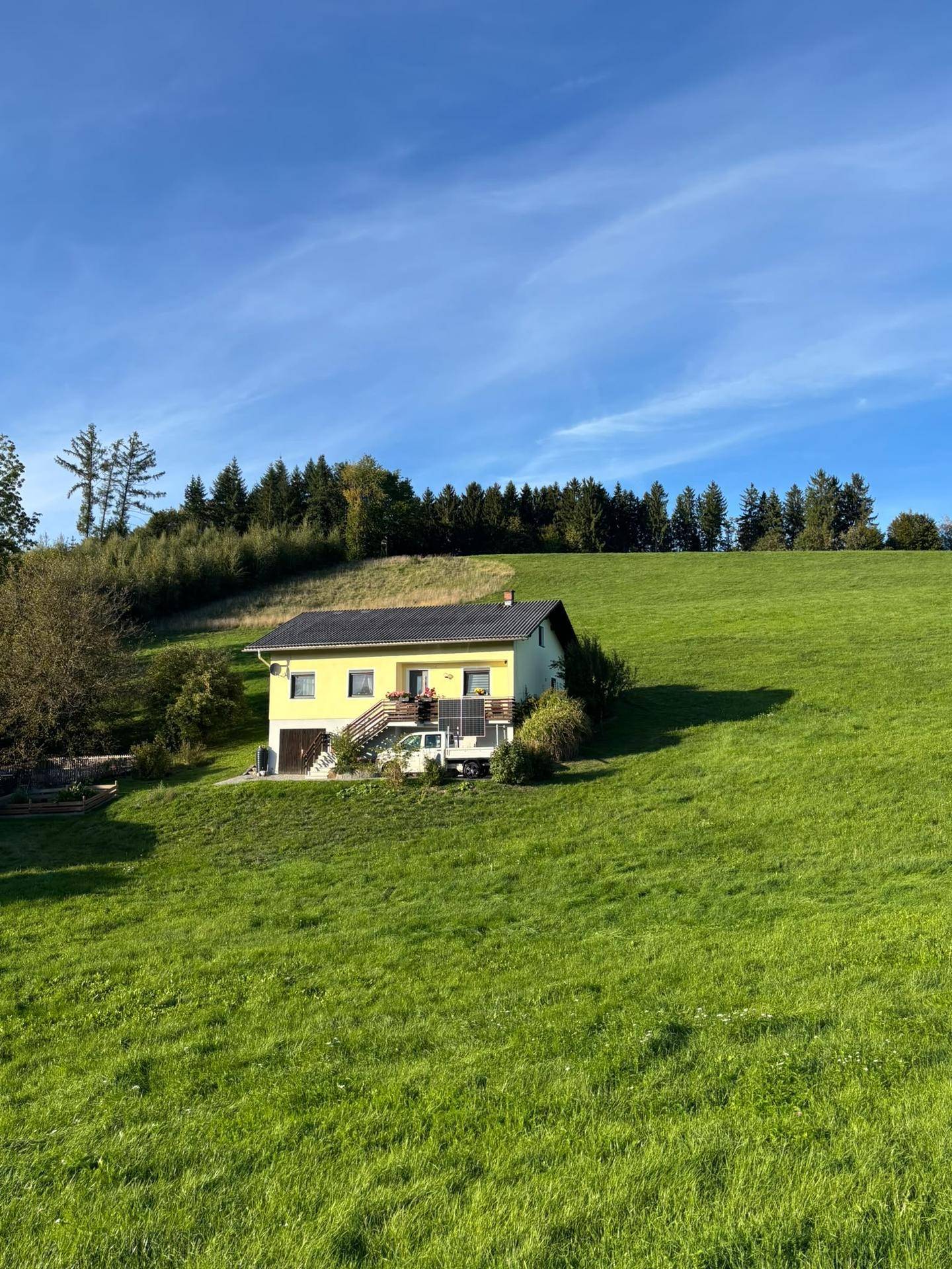 Weitläufige Ansicht des gelben Hauses in ländlicher Umgebung mit weiten grünen Wiesen.