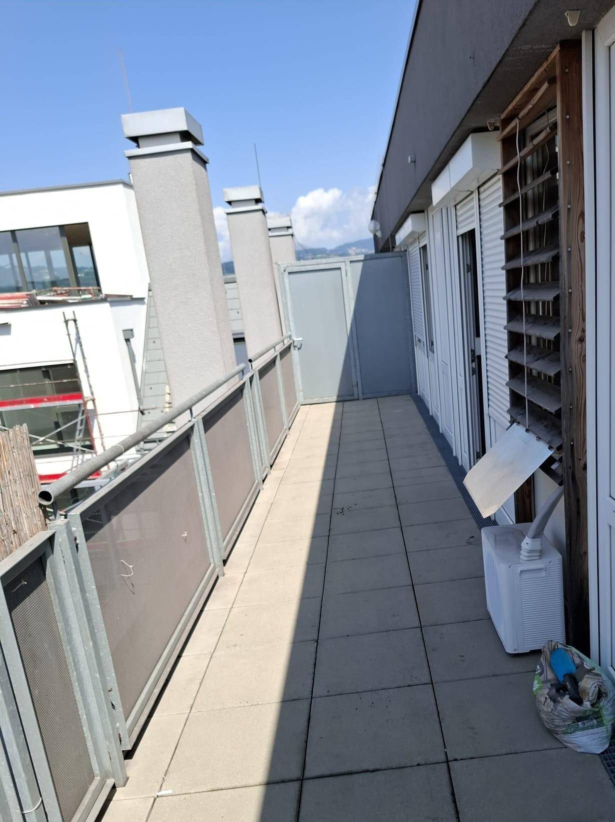 Langer Balkon mit Fliesenboden und Blick auf die Umgebung.