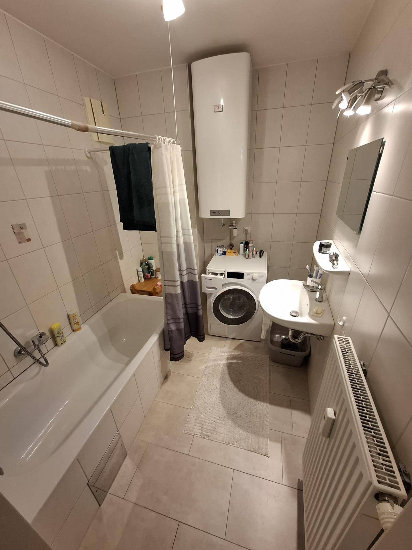 Badezimmer mit Badewanne, Waschbecken, WC und Waschmaschine.
