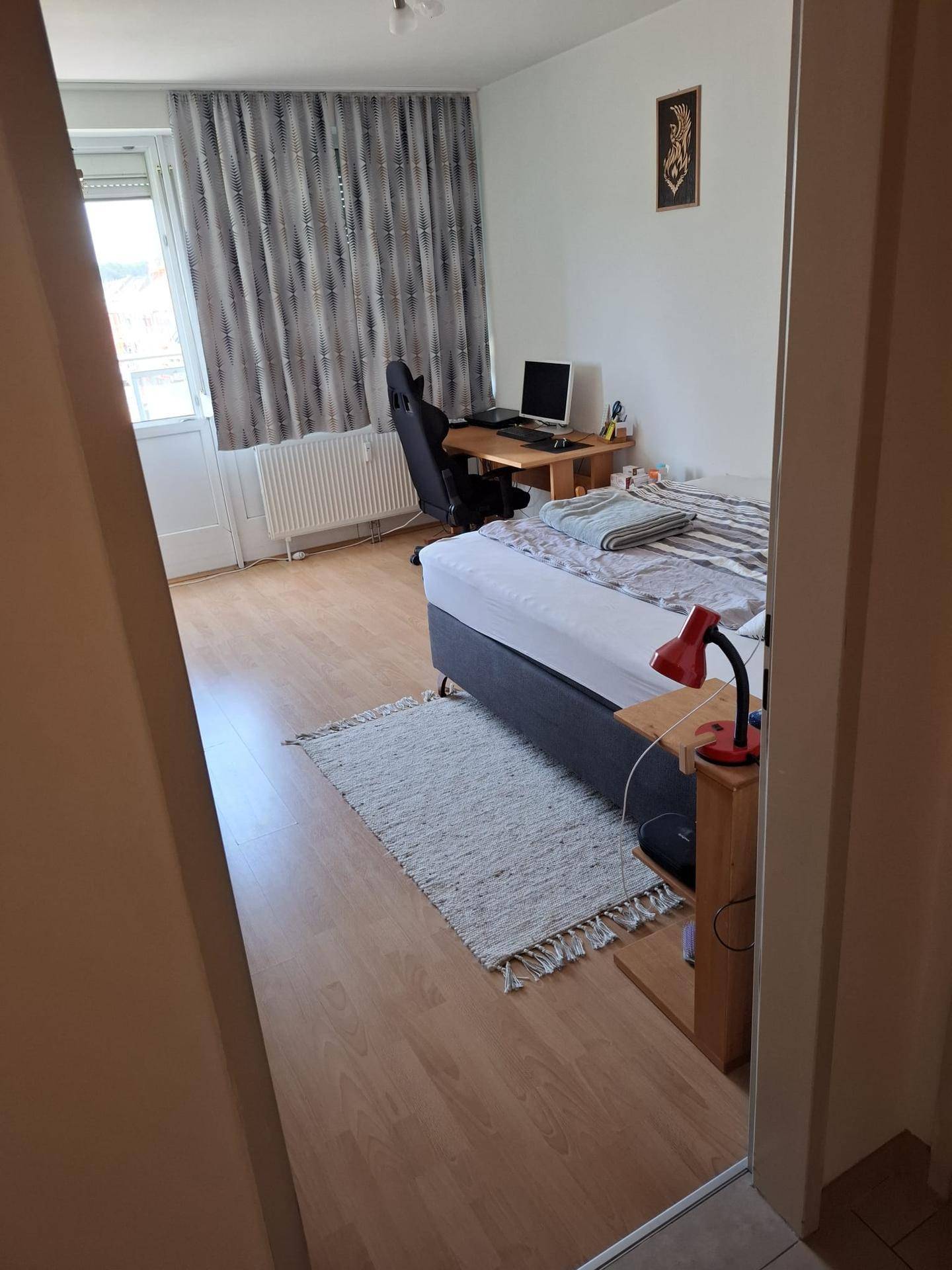 Gemütliches Schlafzimmer mit Holzboden, Bett und Schreibtisch.
