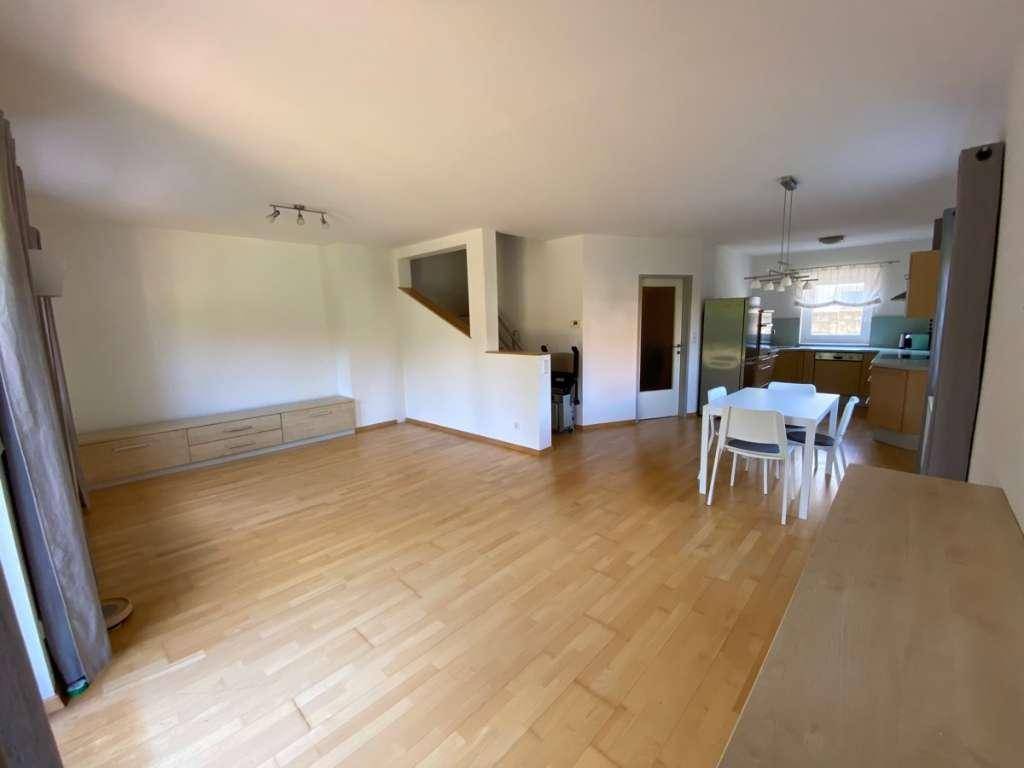Geräumiger Wohn-Essbereich mit Parkettboden und halboffener Küche, ideal für geselliges Beisammensein.