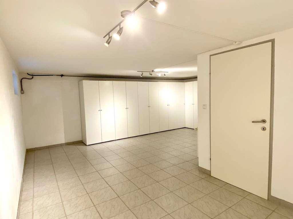 Heller Kellerraum mit praktischen Einbauschränken und Fliesenboden, ideal als Abstellfläche.