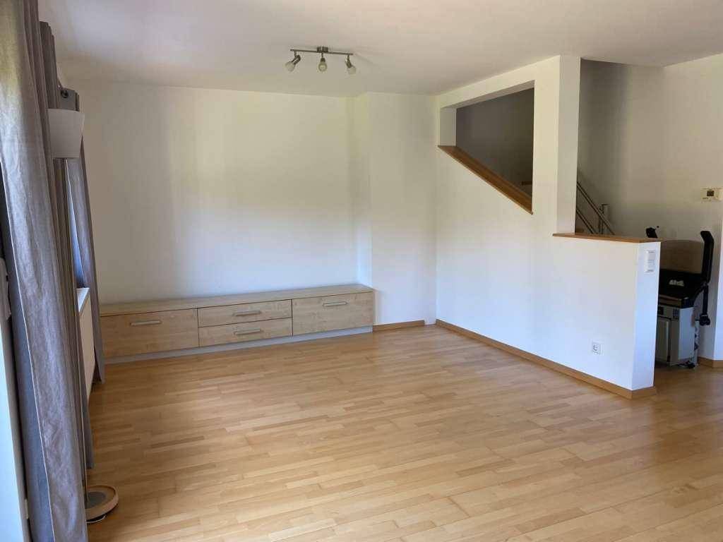 Heller Wohnbereich mit Parkettboden, einem langen Sideboard und Treppenaufgang.