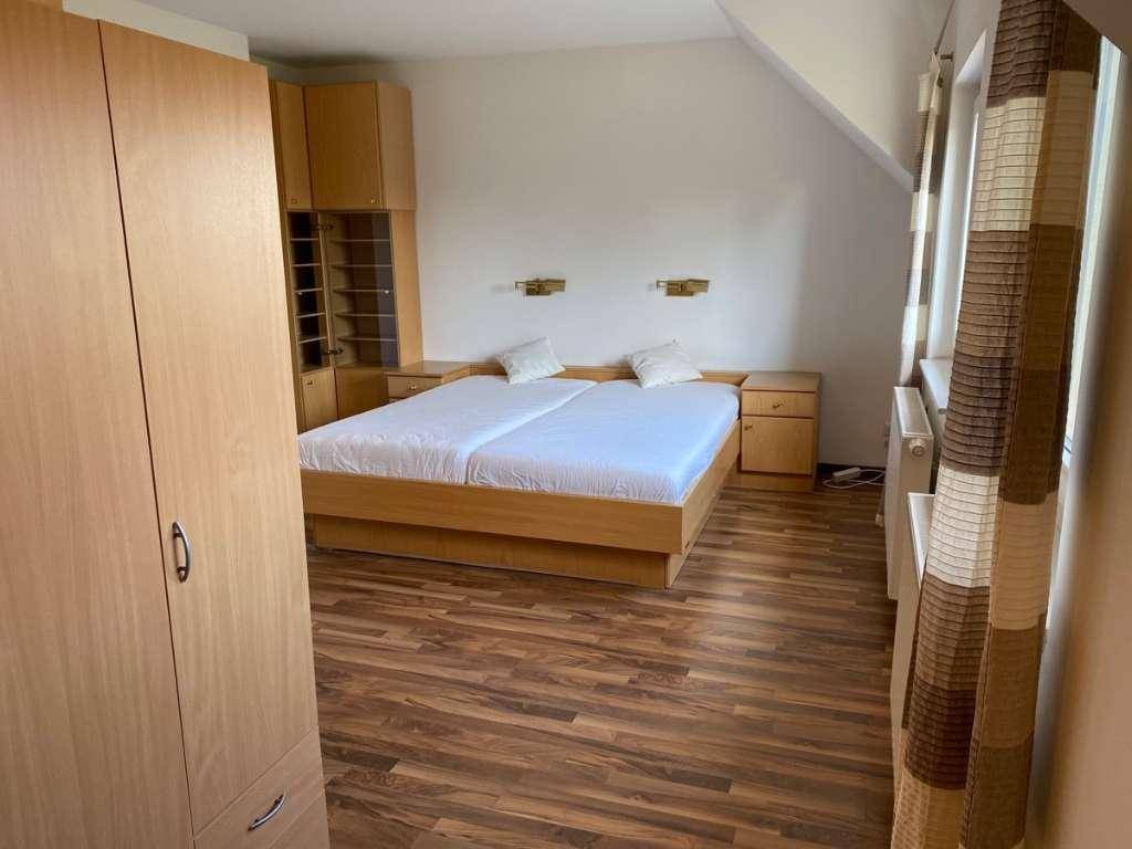 Helles Schlafzimmer mit Doppelbett, Laminatboden und geräumigem Kleiderschrank.