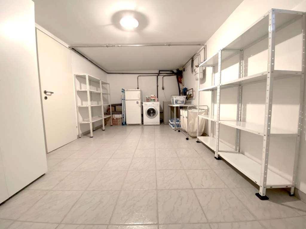 Funktionaler Hauswirtschaftsraum im Keller mit Waschmaschine, Kühlschrank und praktischen Regalen.