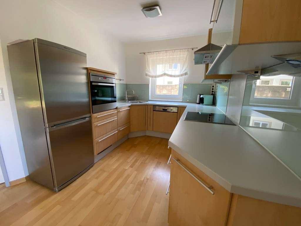 Gut ausgestattete Küche mit Holzfronten, integriertem Backofen und großem Kühlschrank.