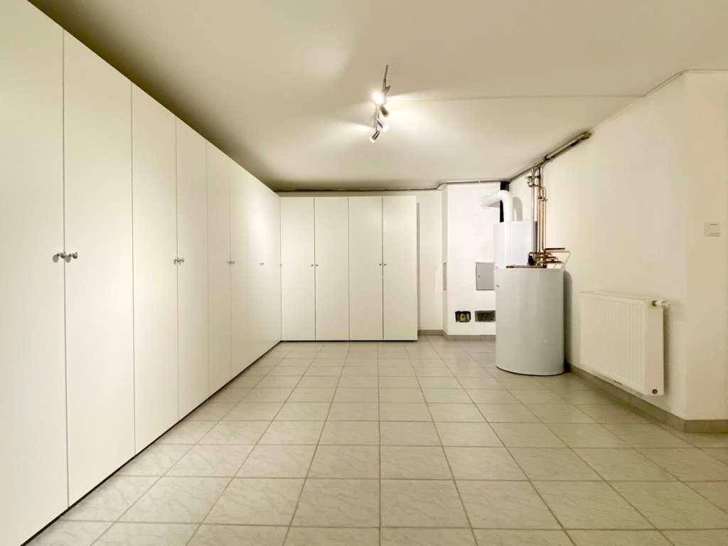 Geräumiger Kellerraum mit Fliesenboden, Einbauschränken und Heizungsanlage.