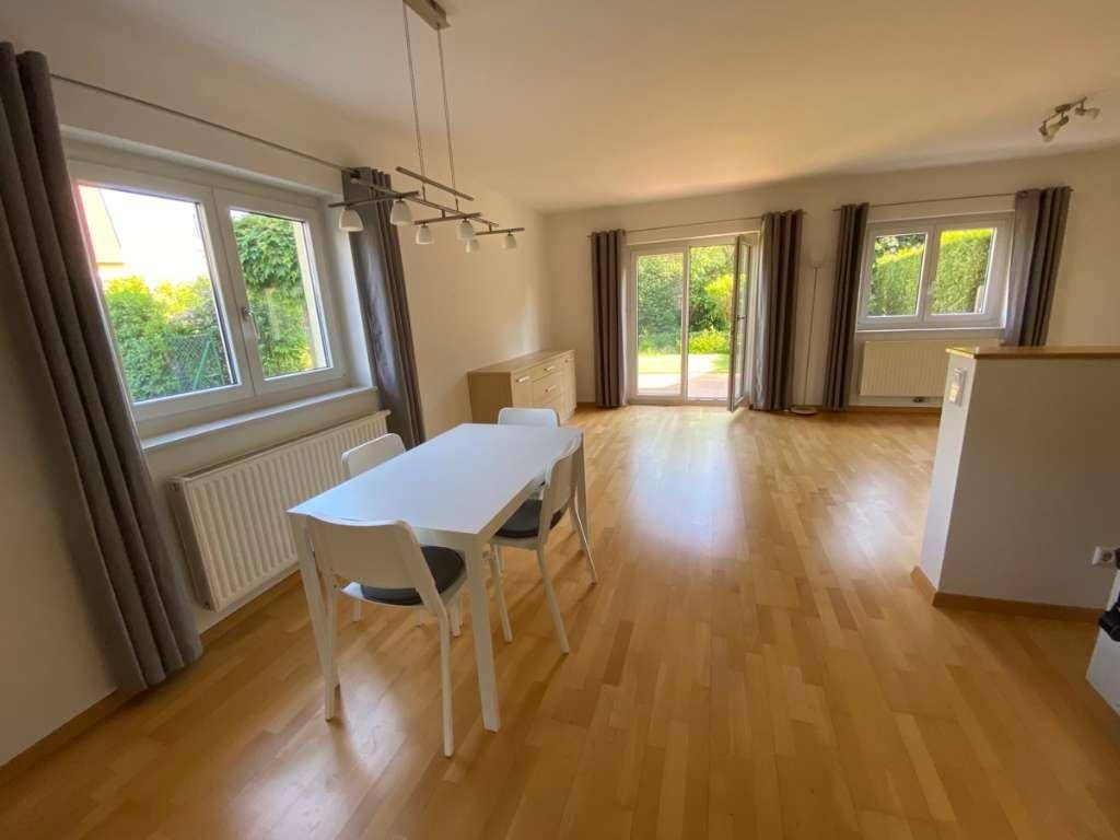 Geräumiger Wohn-Essbereich mit hellem Parkettboden und großen Fenstern zum grünen Garten.