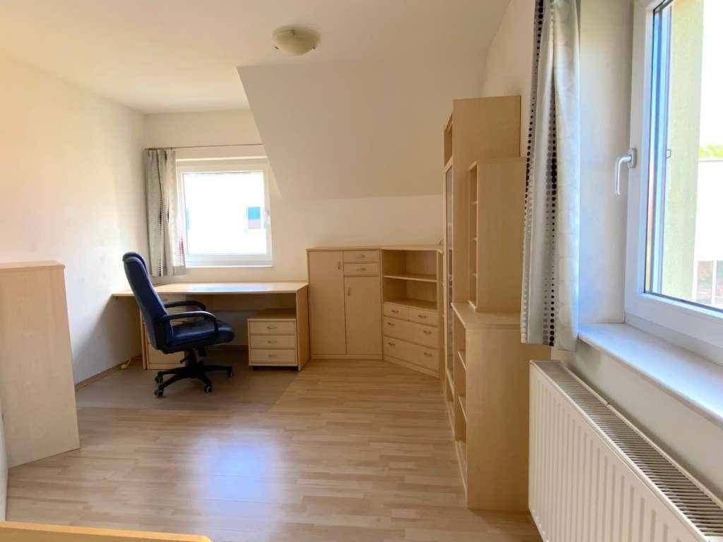 Geräumiges Arbeitszimmer mit Schreibtisch, Bürostuhl und praktischen Regalsystemen.