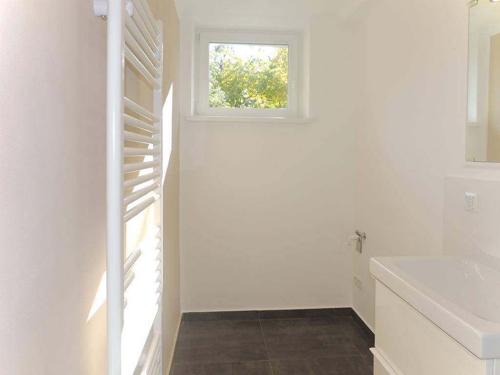Badezimmer mit Fenster, beheiztem Handtuchhalter und modernem Waschtisch.