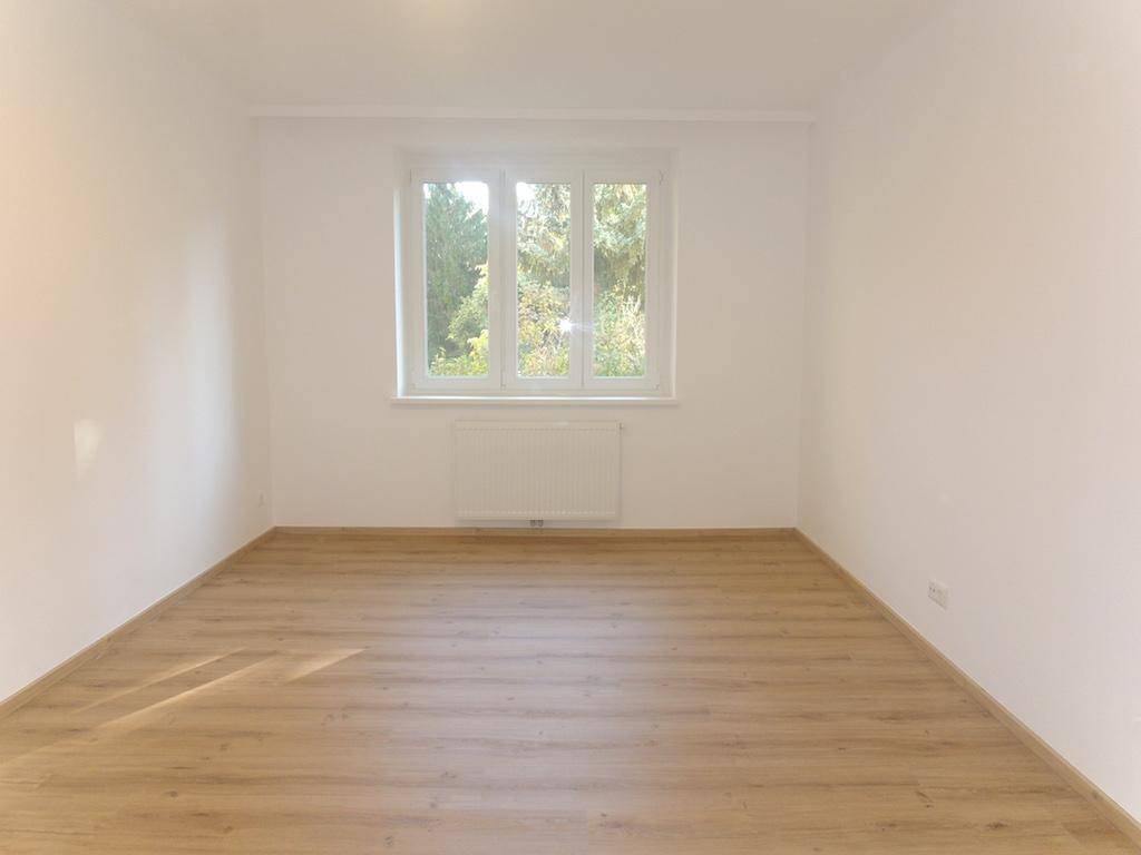 Lichtdurchfluteter Wohnraum mit Laminatboden und weitem Blick auf die umliegende Natur.