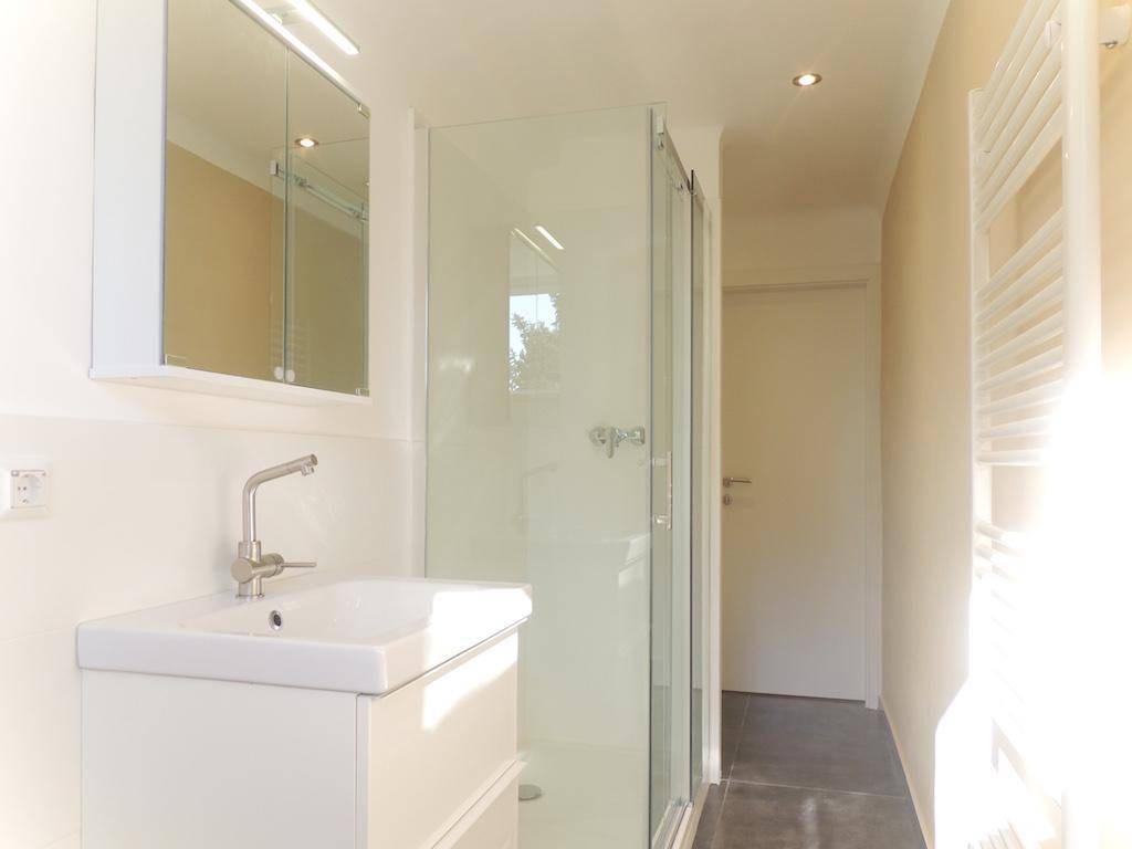 Modernes Badezimmer mit Duschkabine, Waschtisch und beheiztem Handtuchhalter.
