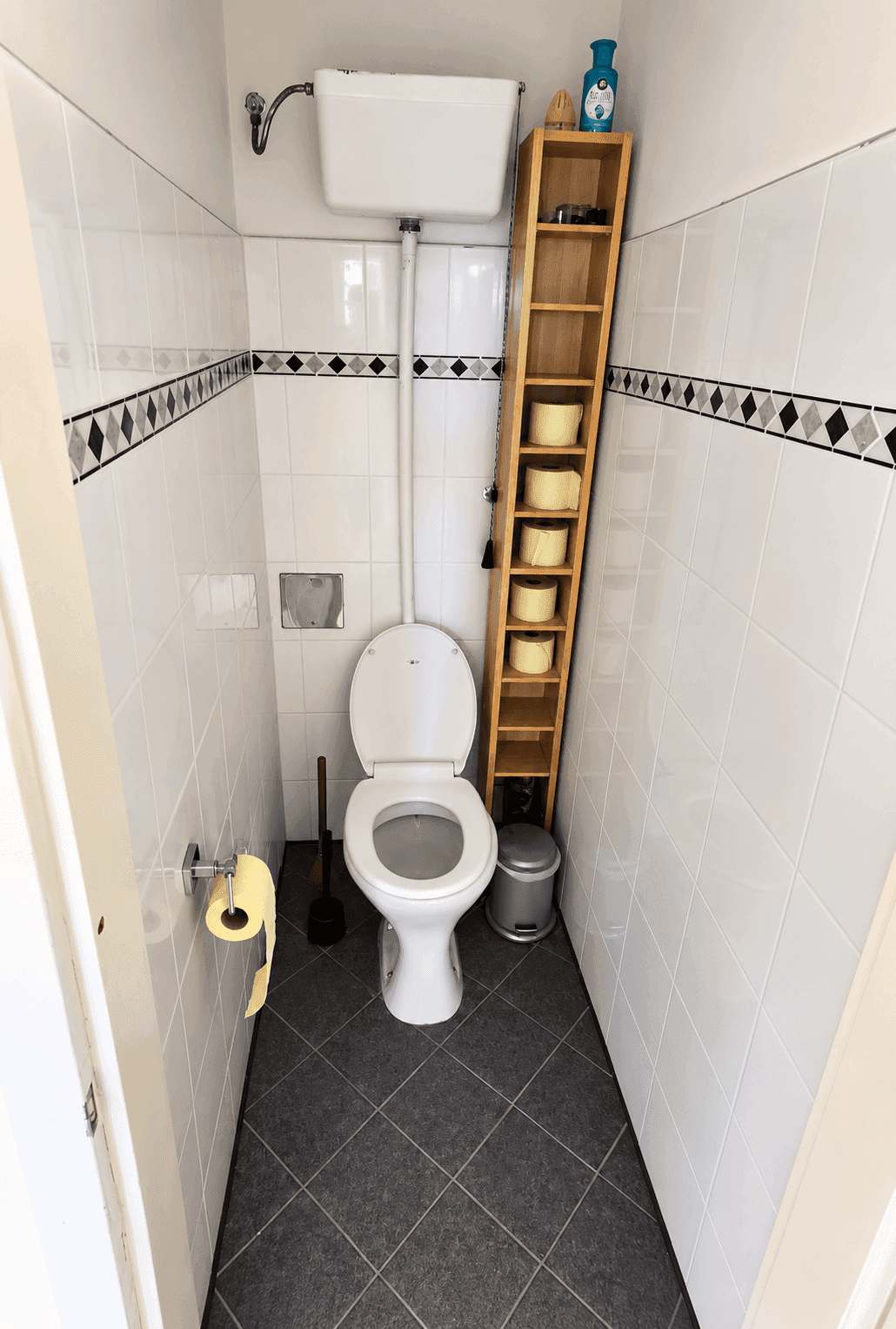 Kleines Gäste-WC mit Toilette, Waschbecken und weißen Wandfliesen.