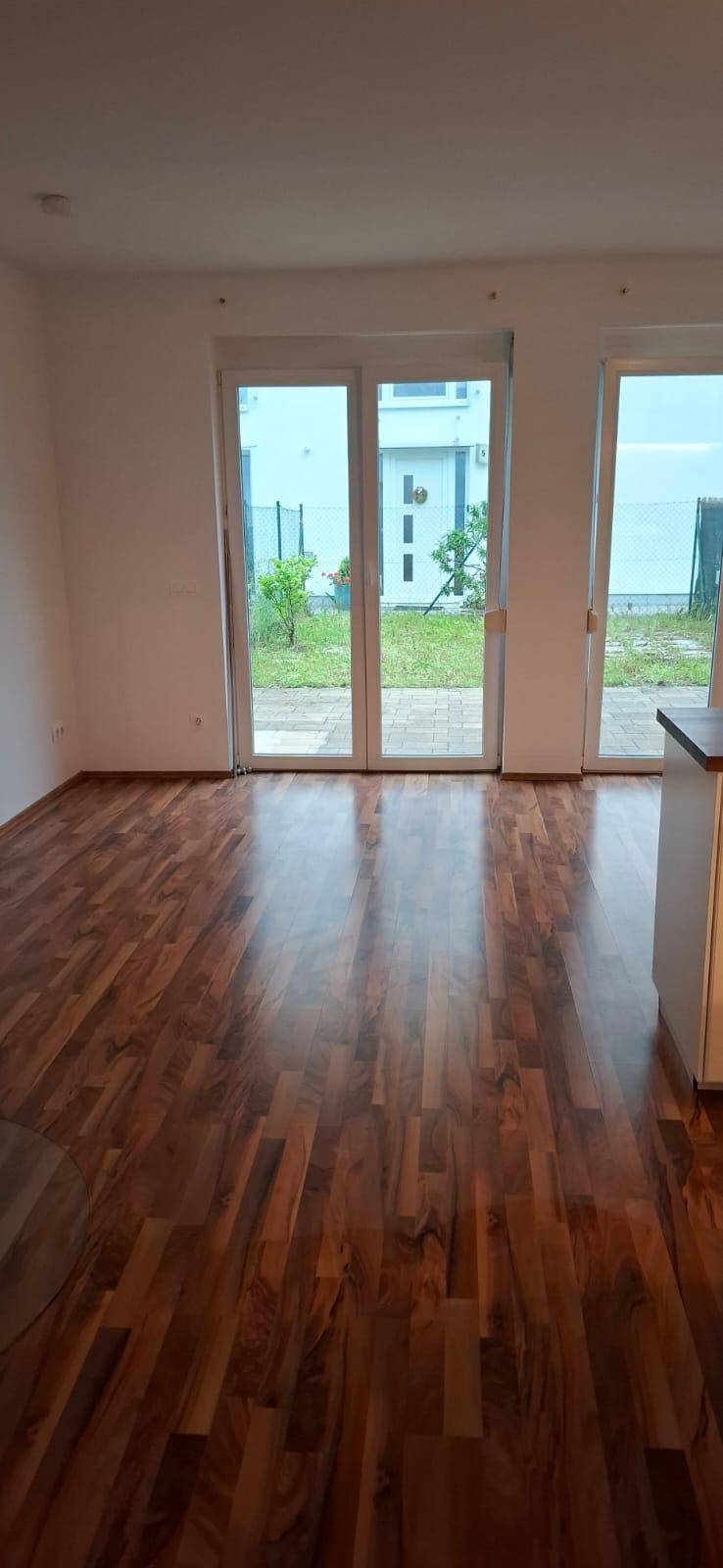 Heller Wohnbereich mit Holzboden und großen Fenstern zum Garten.
