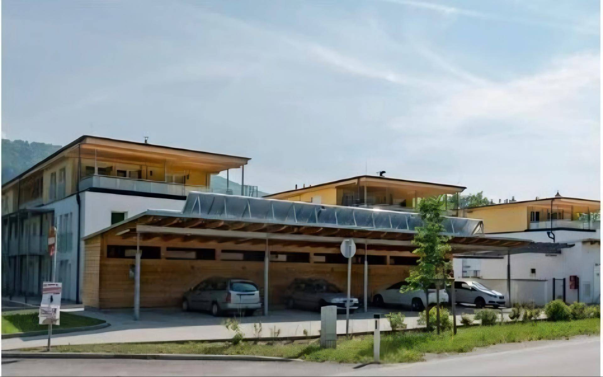 Überdachter Parkplatzbereich mit mehreren Stellplätzen und Solaranlagen auf dem Dach.