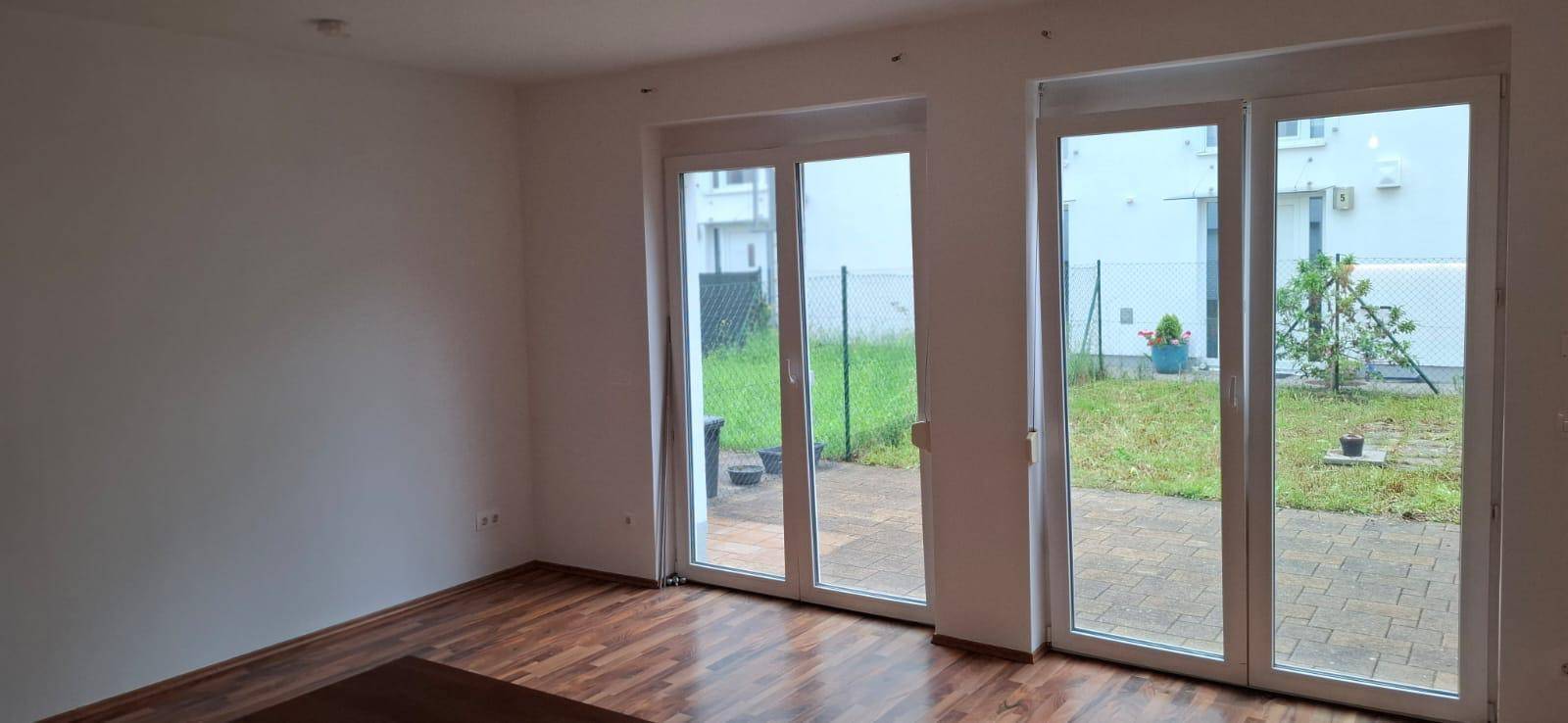 Geräumiger Wohnbereich mit Holzboden und Zugang zu einer Terrasse oder Garten.