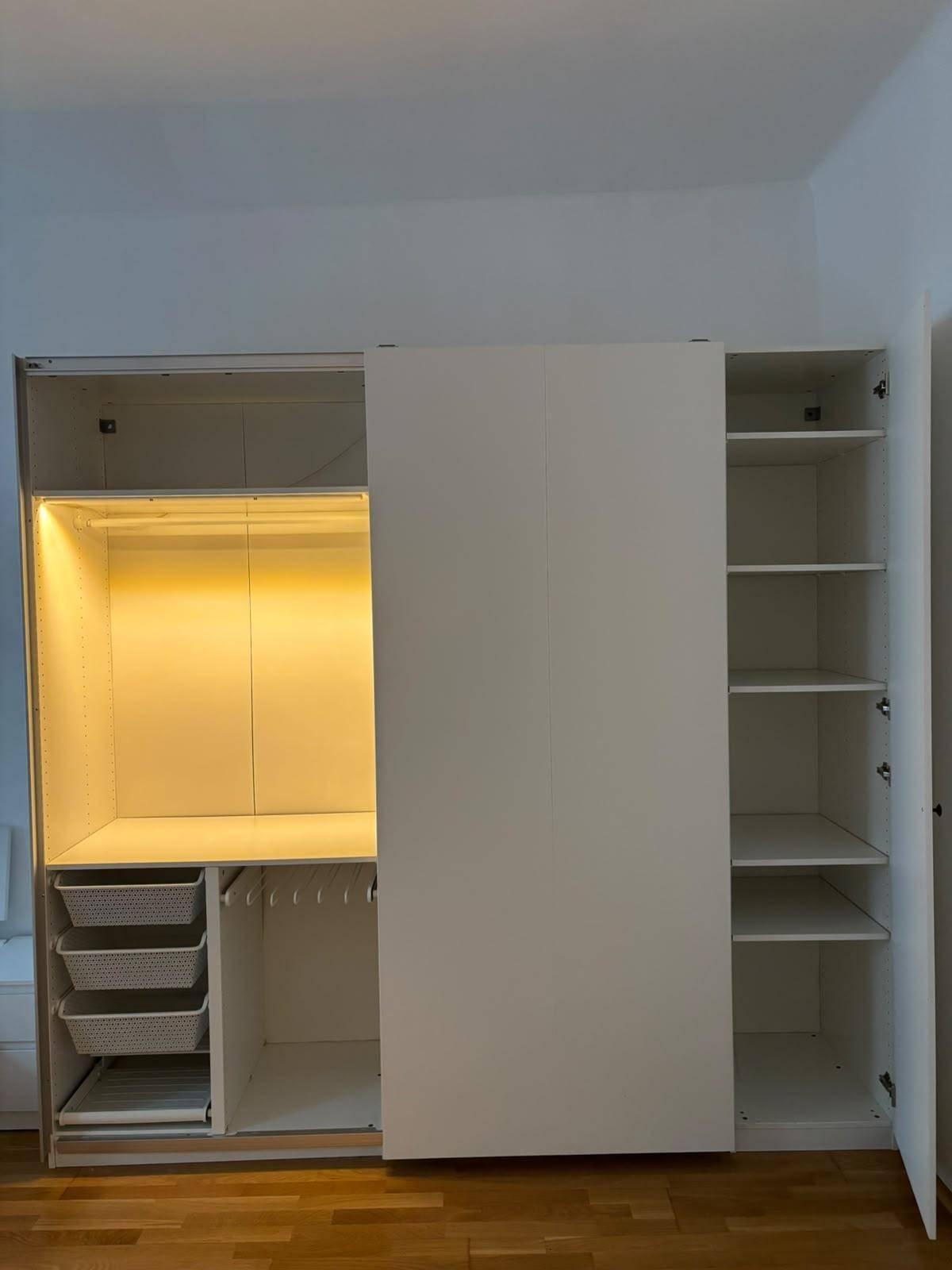 Offener Kleiderschrank mit integrierter Beleuchtung, Regalen und Schubladen für Stauraum.