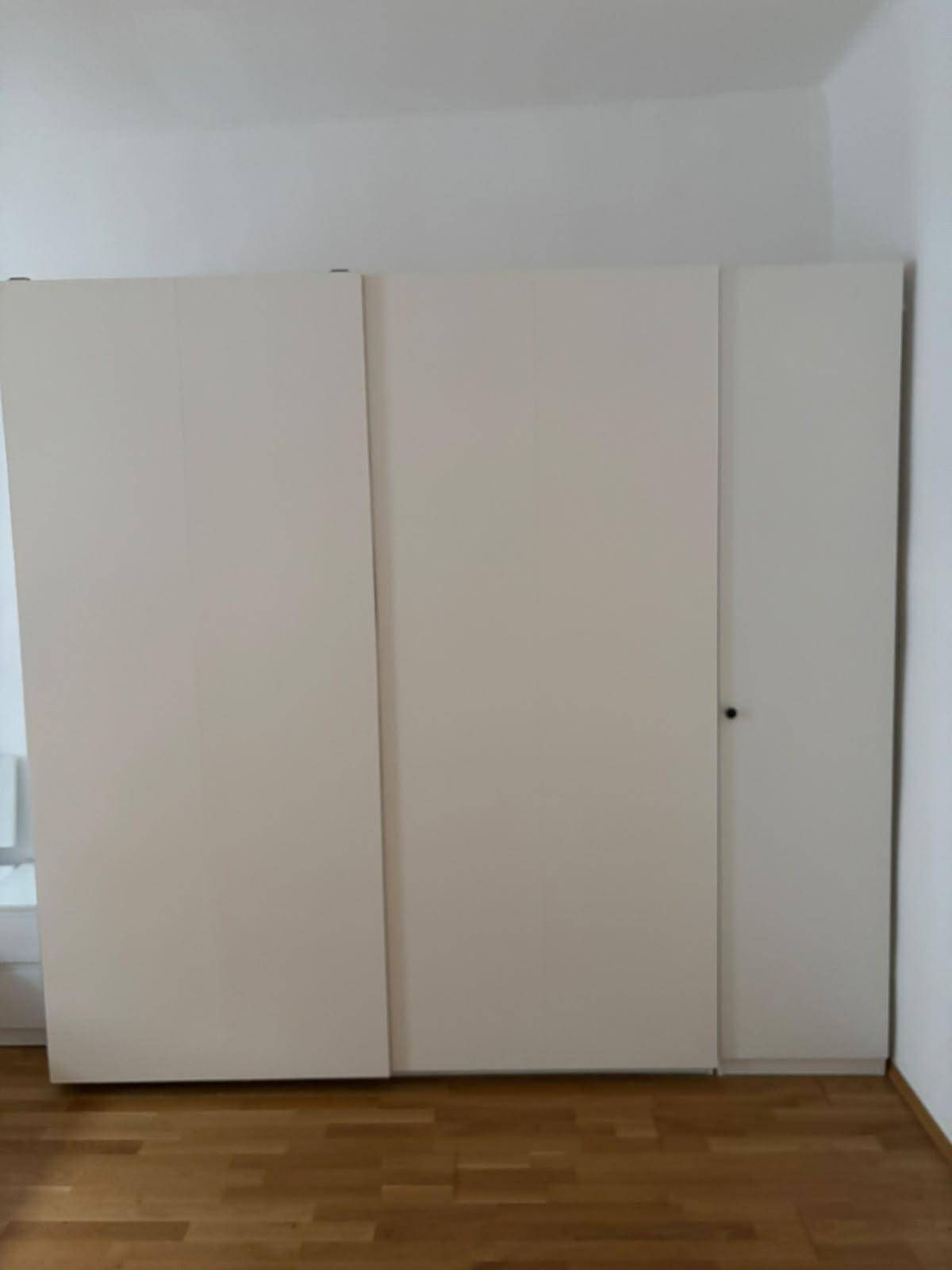 Geschlossener weißer Kleiderschrank im Schlafzimmer, der viel Stauraum bietet.
