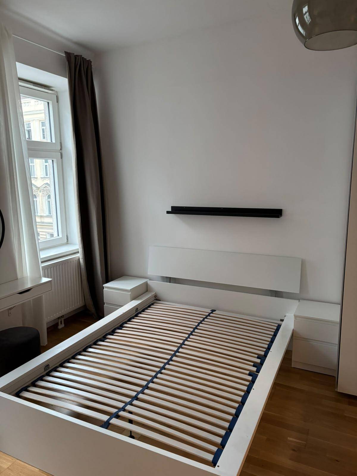 Detailansicht des Bettgestells mit Lattenrost und integrierten Nachttischen im Schlafzimmer.