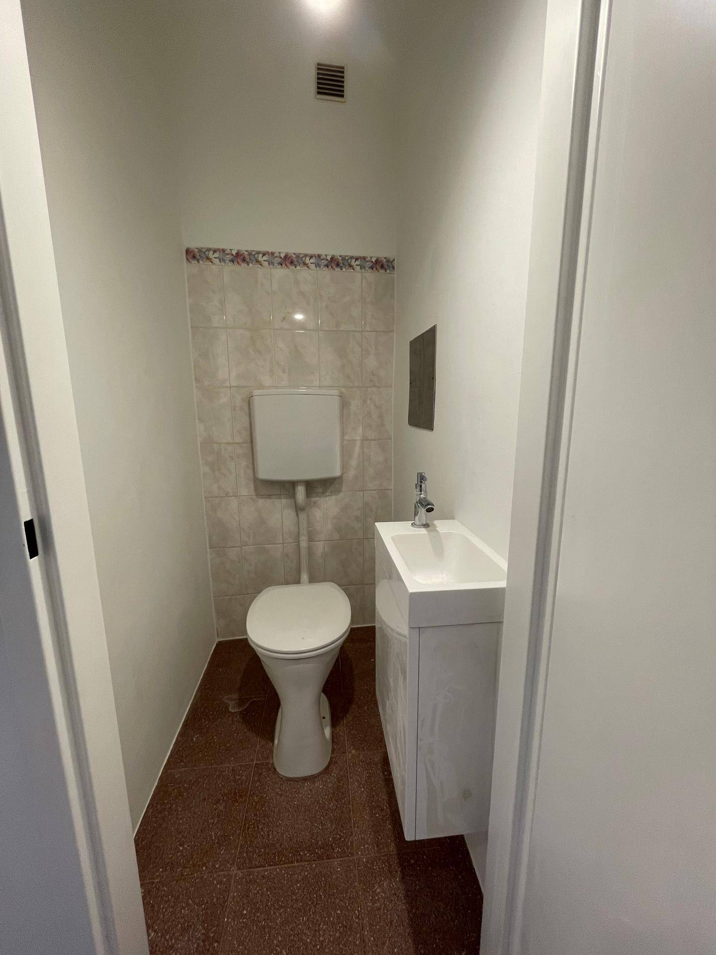 Kleines Gäste-WC mit Toilette, Waschbecken und dekorativen Fliesen an der Wand, funktional und sauber.