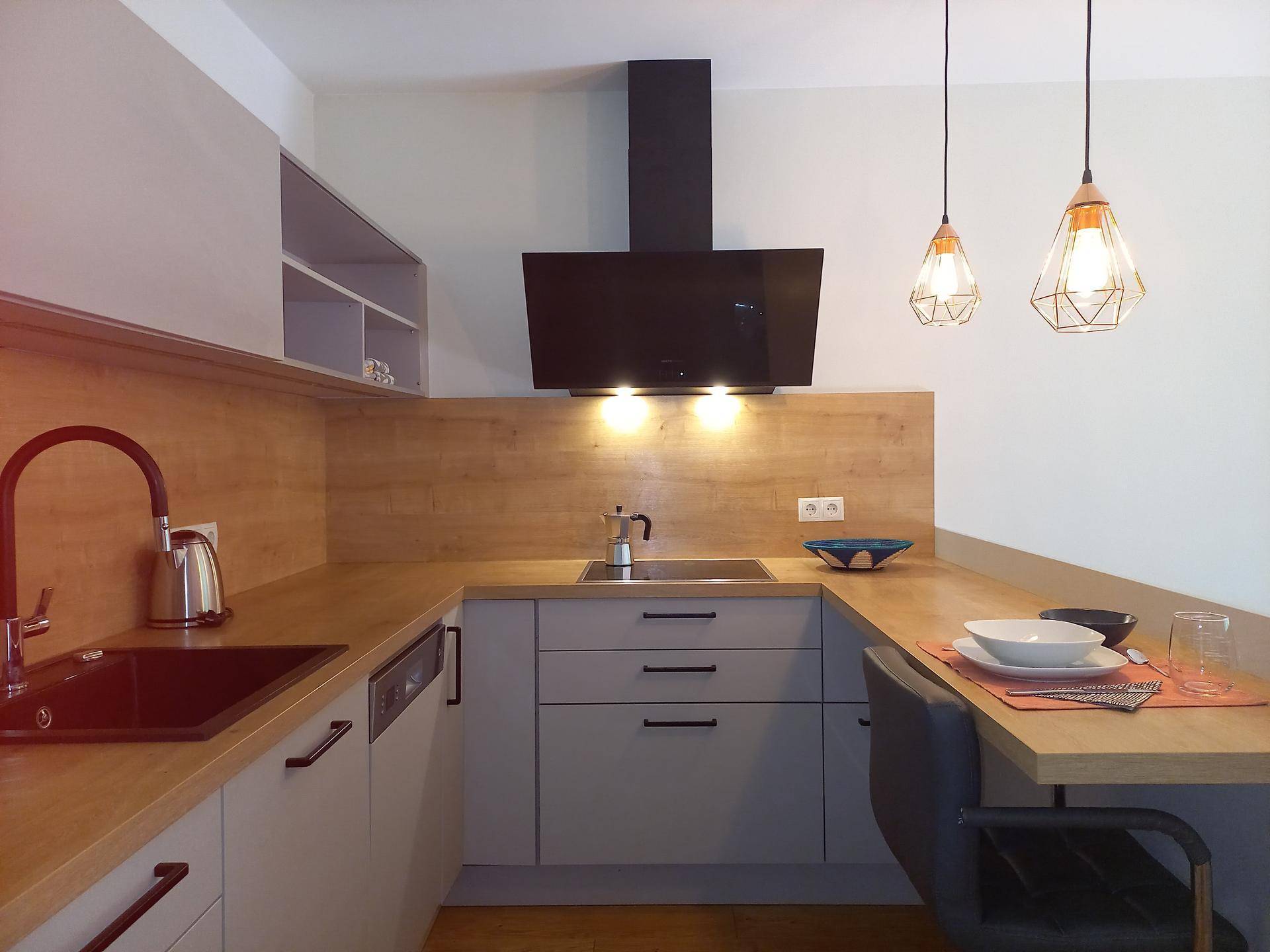 Moderne Küchenzeile mit Holz-Arbeitsplatte, integriertem Spülbecken und stylischen Hängelampen.