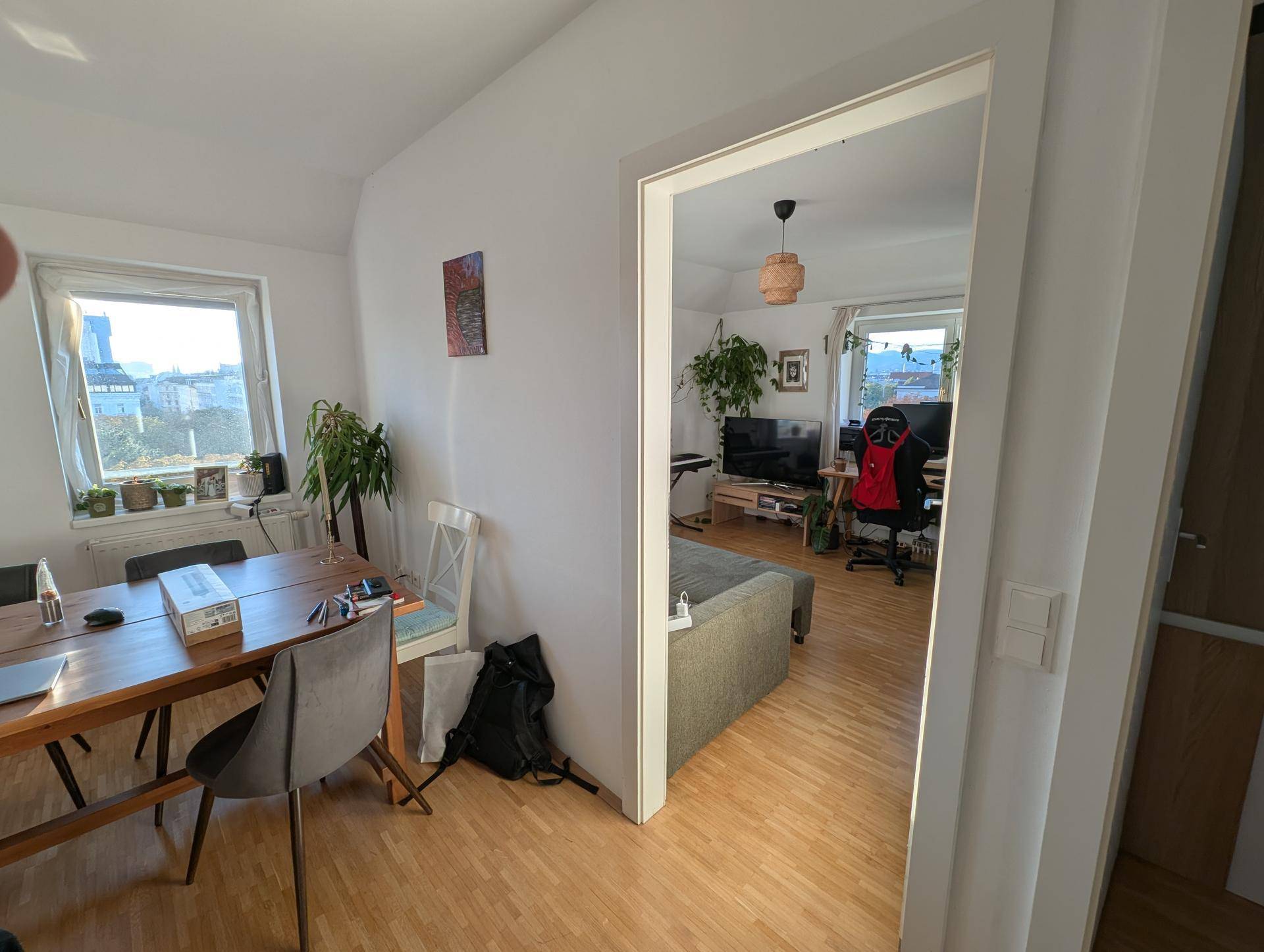 Essbereich mit Holztisch und Stühlen, der in einen weiteren Wohnbereich übergeht.