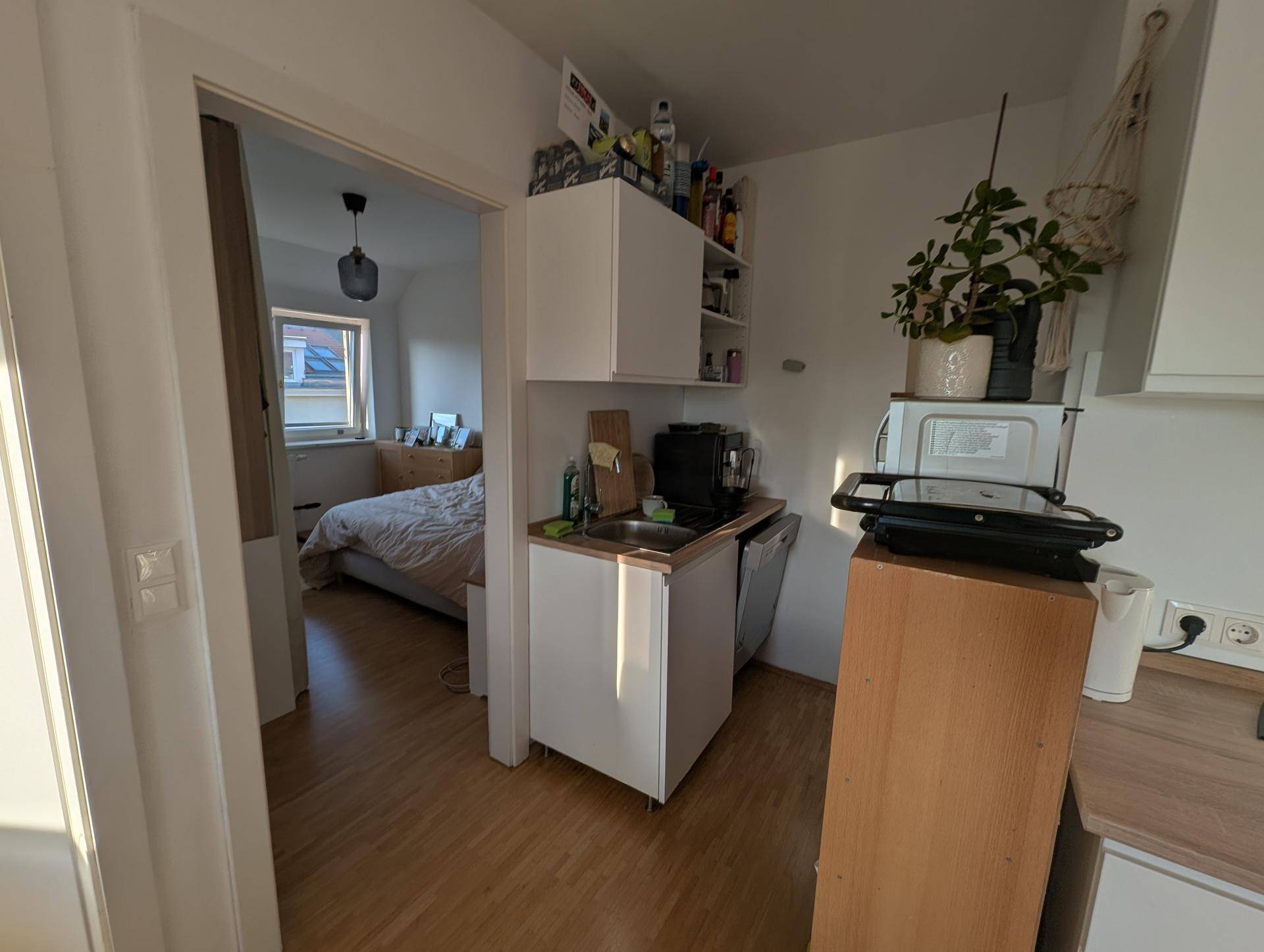 Kleine Küchenzeile mit Spüle und Blick in ein angrenzendes Schlafzimmer.