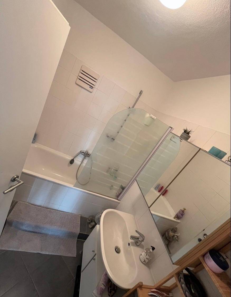 Badezimmer mit Badewanne, Duschwand und Einzelwaschbecken.