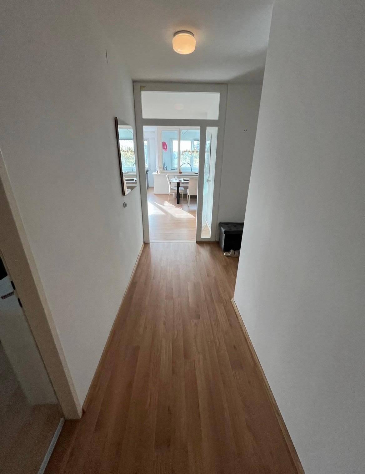 Heller Flur mit Holzfußboden, der zum Essbereich führt.