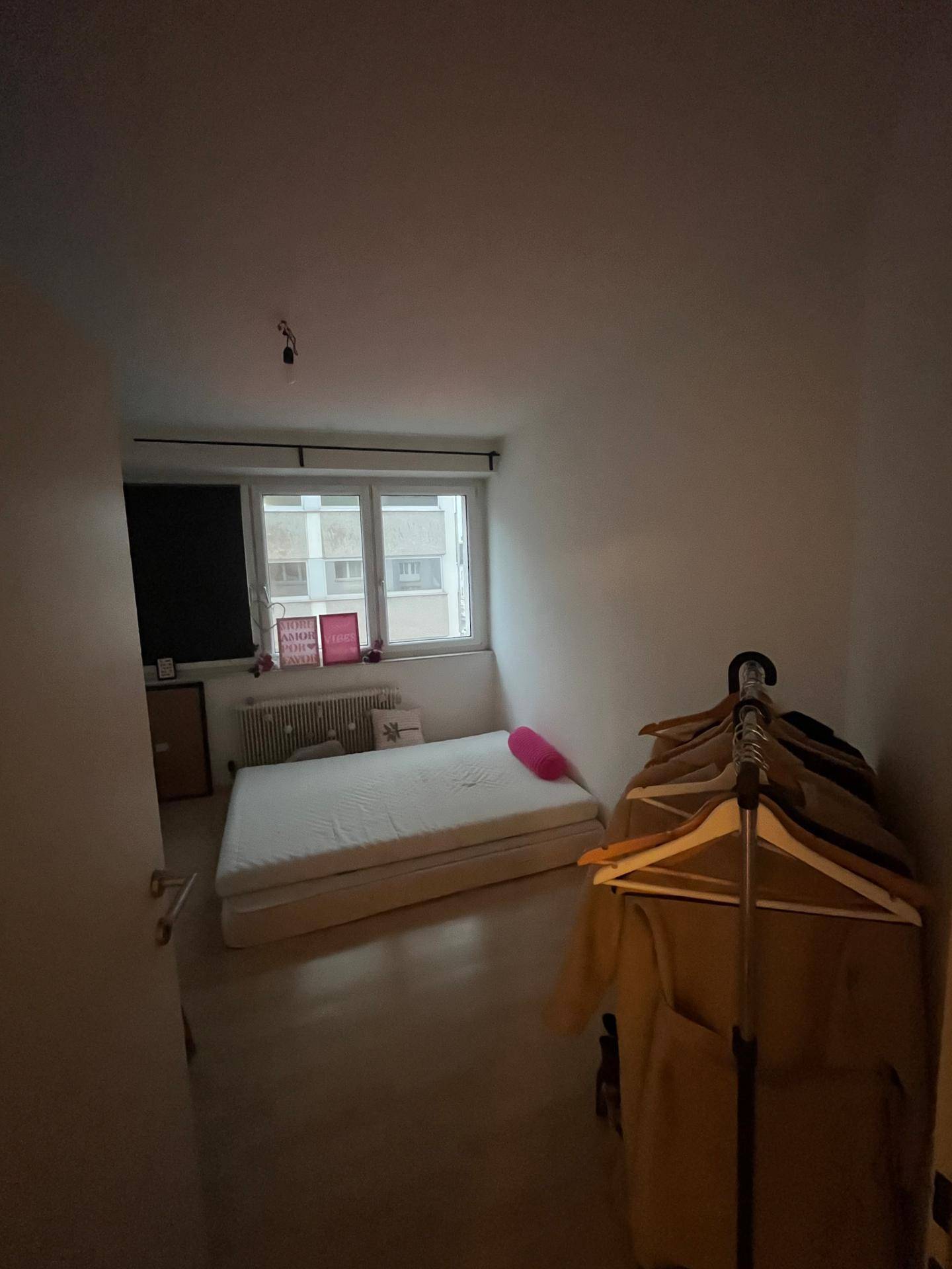 Kleines Schlafzimmer mit Matratze auf dem Boden und Fenster.
