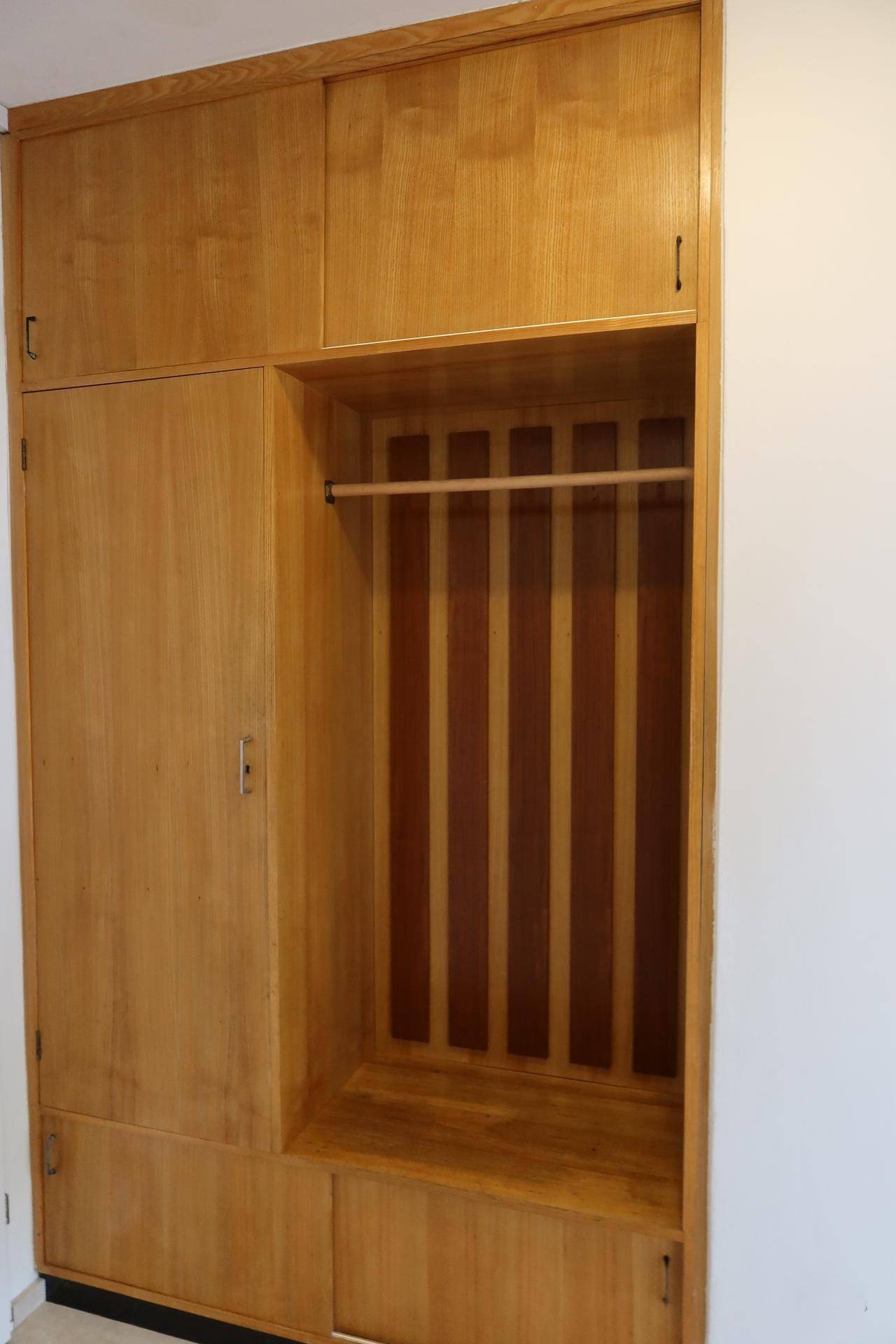Einbauschrank aus Holz im Flur mit Garderobenstange und Ablageflächen.