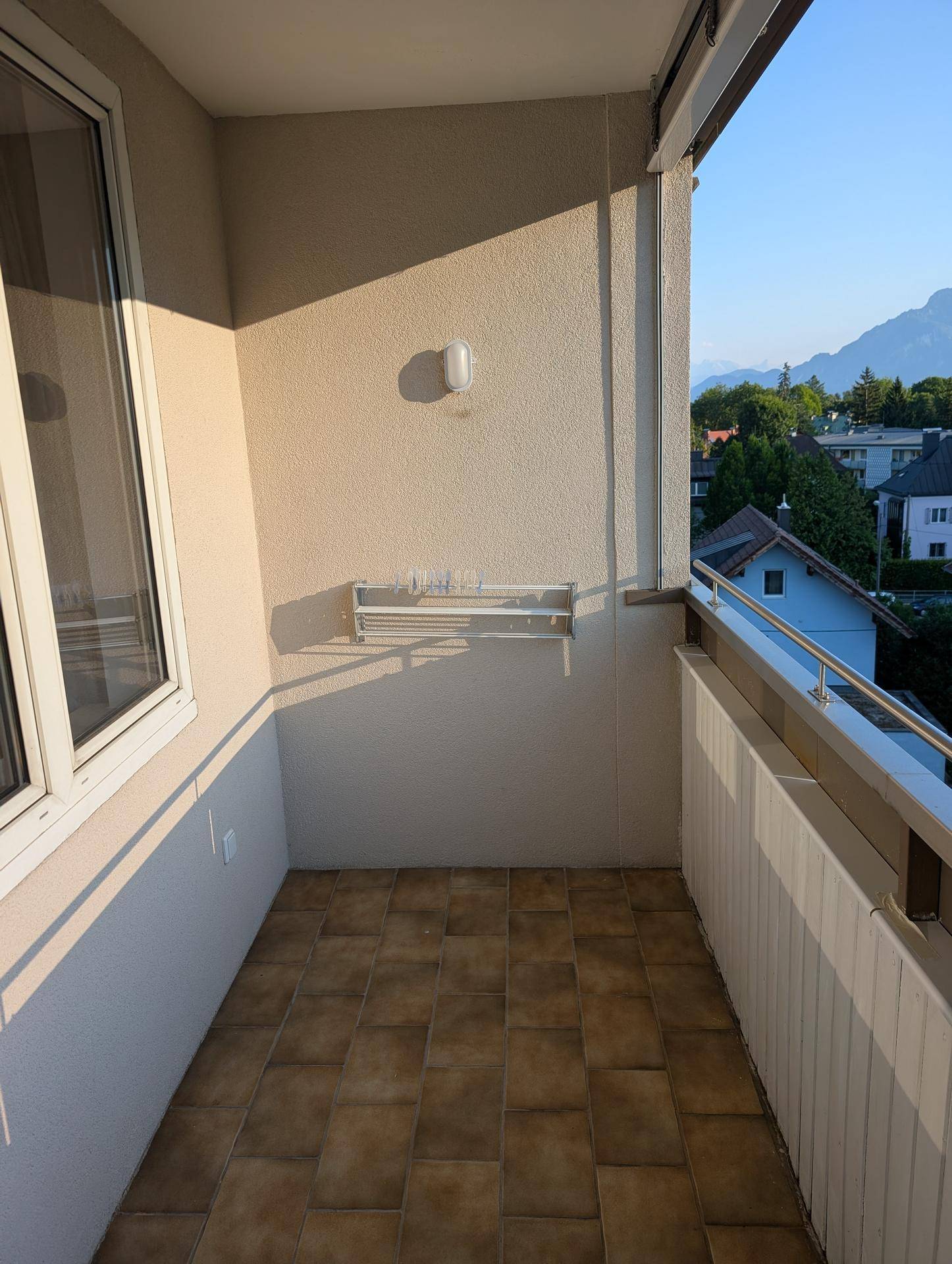 Balkon mit Fliesenboden und Wäscheständer, bietet einen Blick auf die Umgebung.