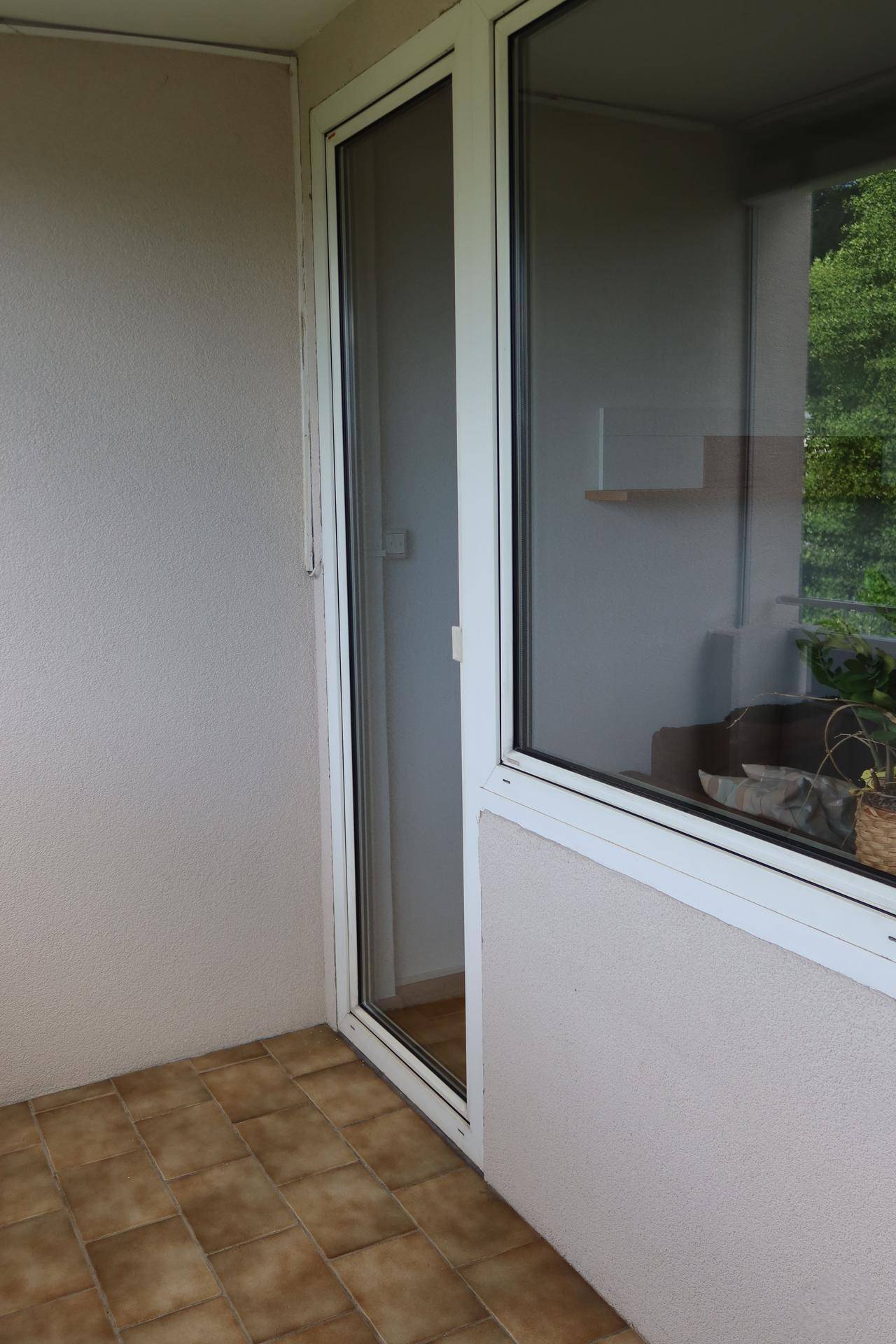 Gefliester Balkonbereich mit Blick auf die grüne Umgebung und viel Tageslicht.
